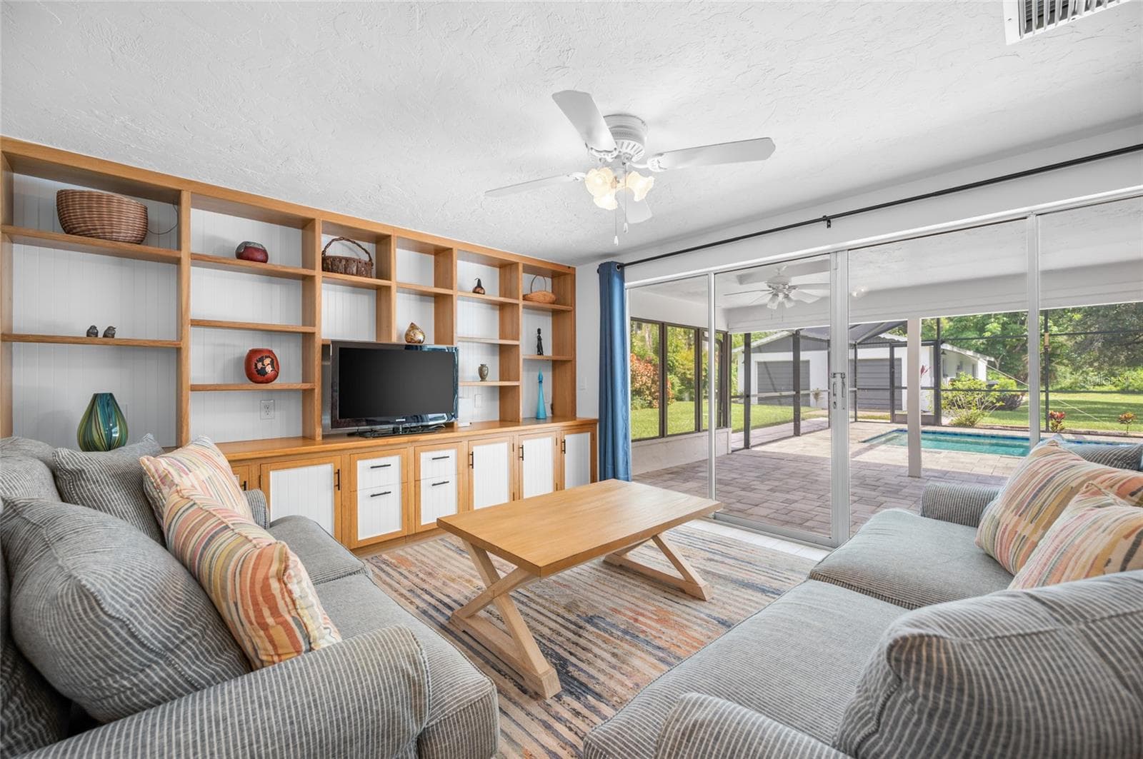 Living room with built in shelving and sliders opening to the lanai - 2111 HEASLEY RD, ENGLEWOOD