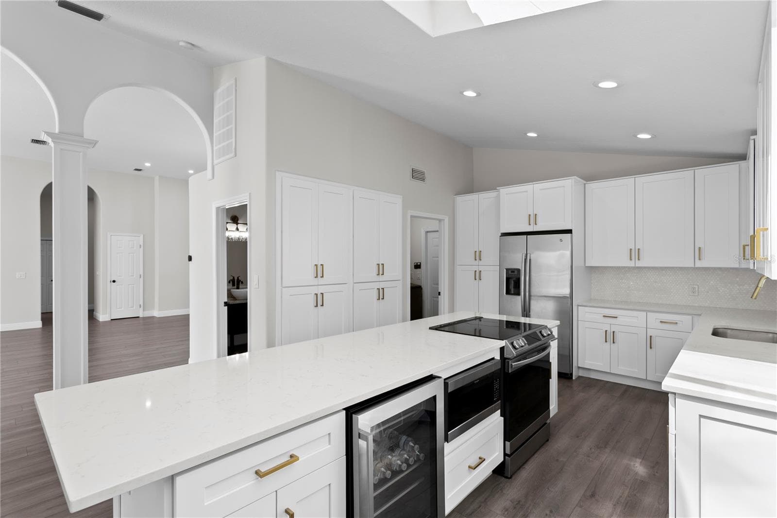 Well-appointed kitchen island featuring a wine refrigerator, microwave, range, additional cabinet storage and breakfast bar seating. - 6402 RUBIA CIR, APOLLO BEACH