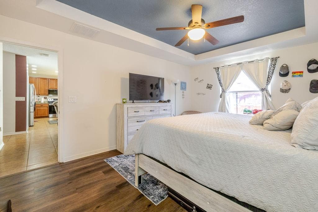 Primary bedroom with ceiling fan and vinyl plank floors - 252 SHERRI LEE LN, DELAND