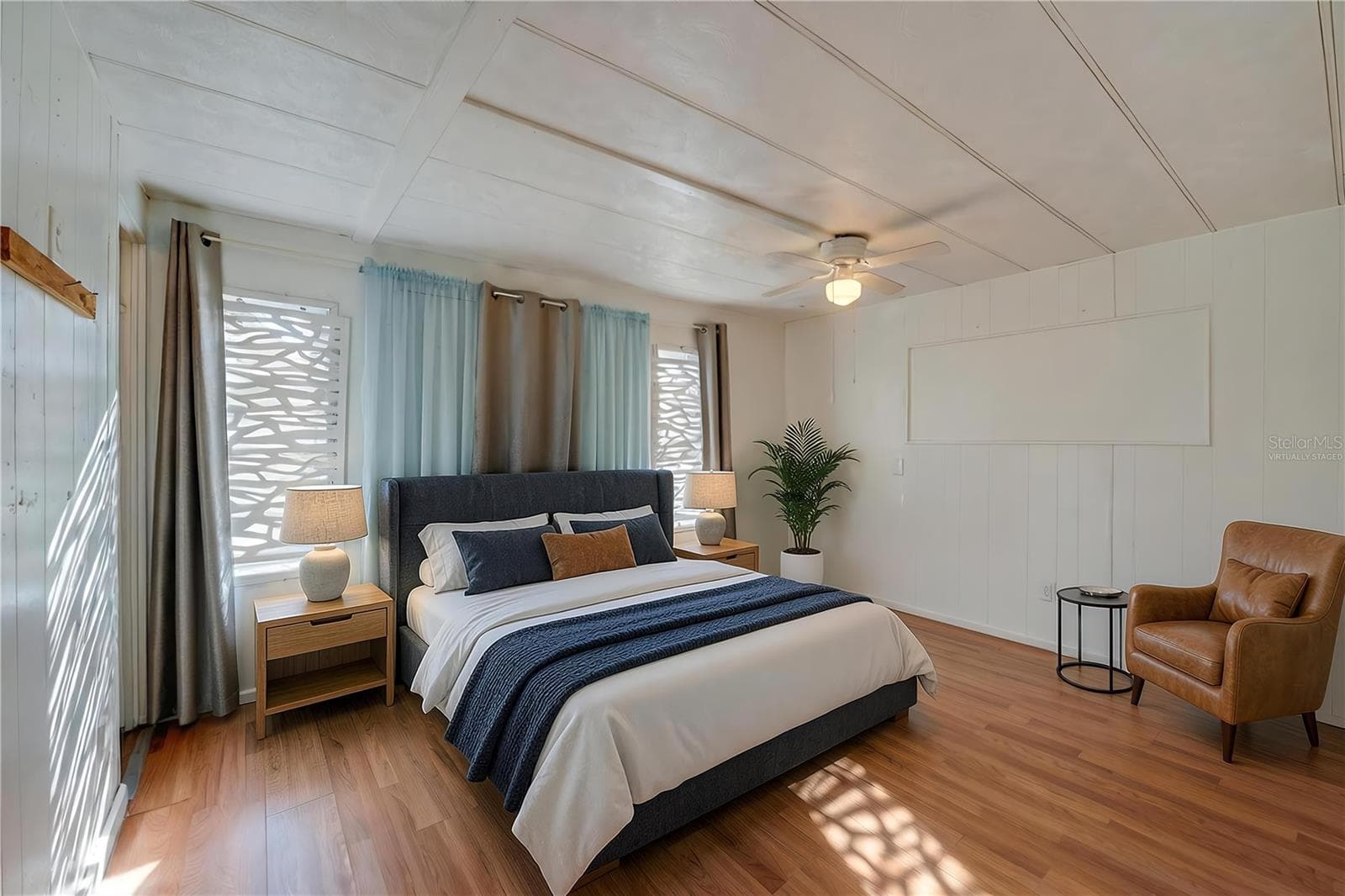 Virtually Staged - Spacious bedroom with paneled walls, a ceiling fan, and multiple windows that bring in abundant natural light. - 128 KON TIKI TER, PORT ORANGE