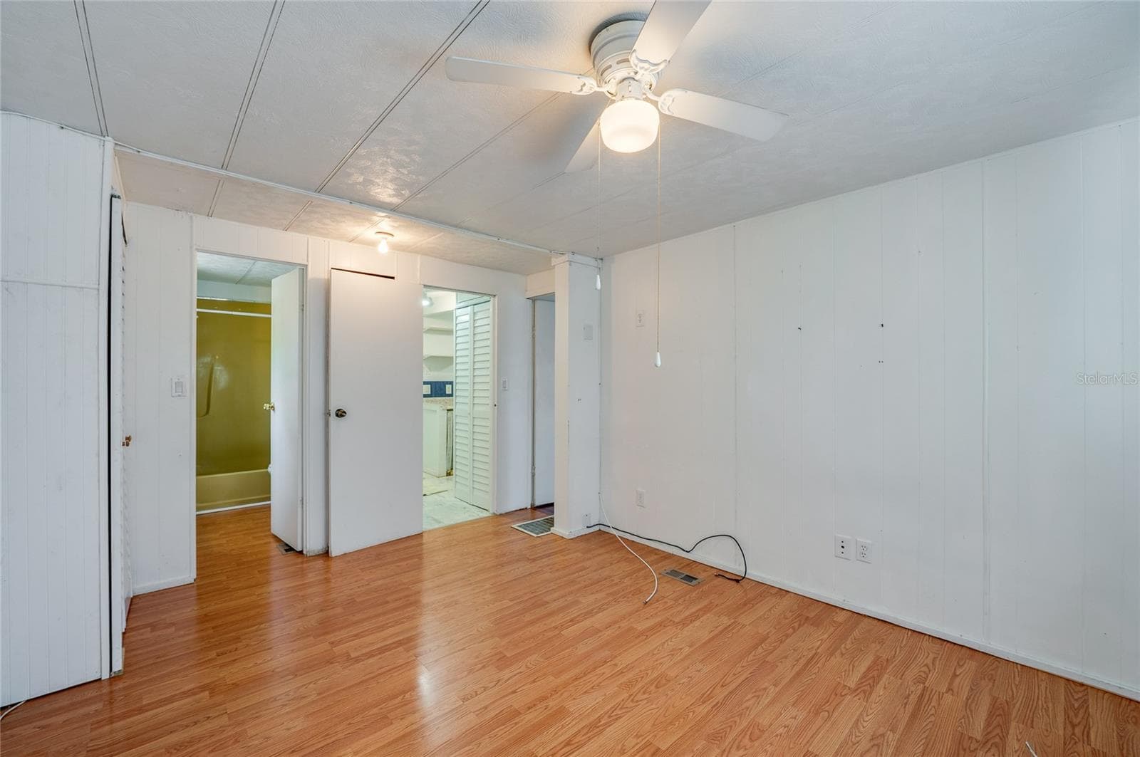 Another view highlights the room’s generous open floor area, ceiling fan, and convenient access to the adjoining bath and nearby living spaces. - 128 KON TIKI TER, PORT ORANGE