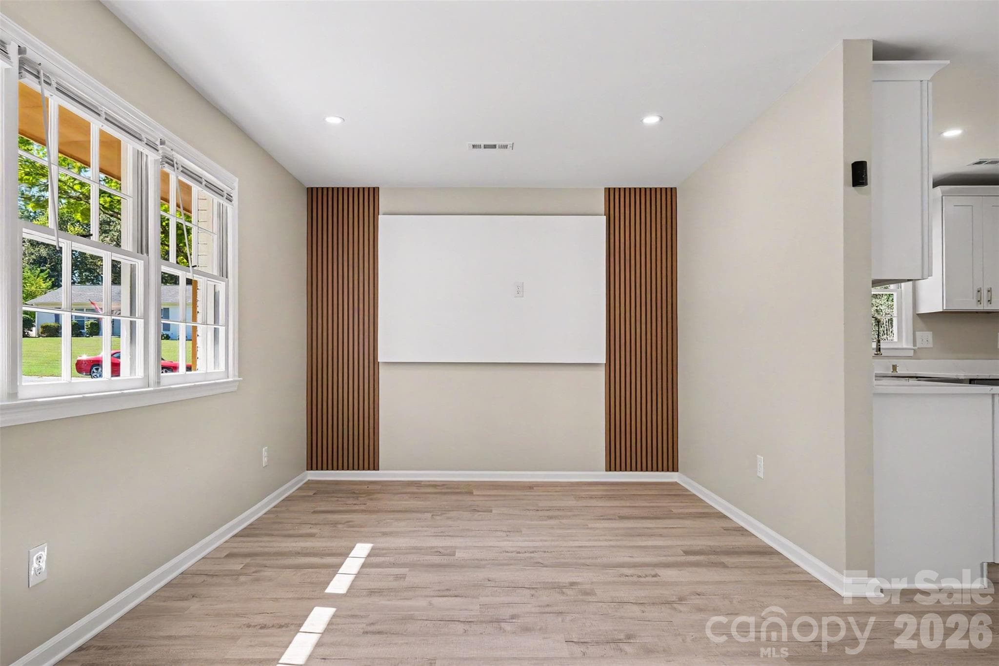 Bright living area highlighted by a stylish wood-accent feature wall, ideal for media and TV placement. - 3801 Hillock Court, Charlotte