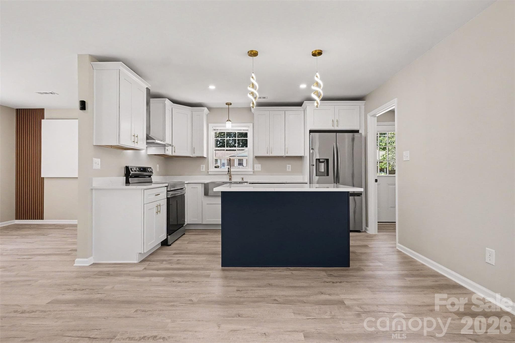 Show-stopping kitchen with a stylish navy center island, modern pendant lighting, brand-new cabinetry, and seamless sightlines to the main living space. - 3801 Hillock Court, Charlotte