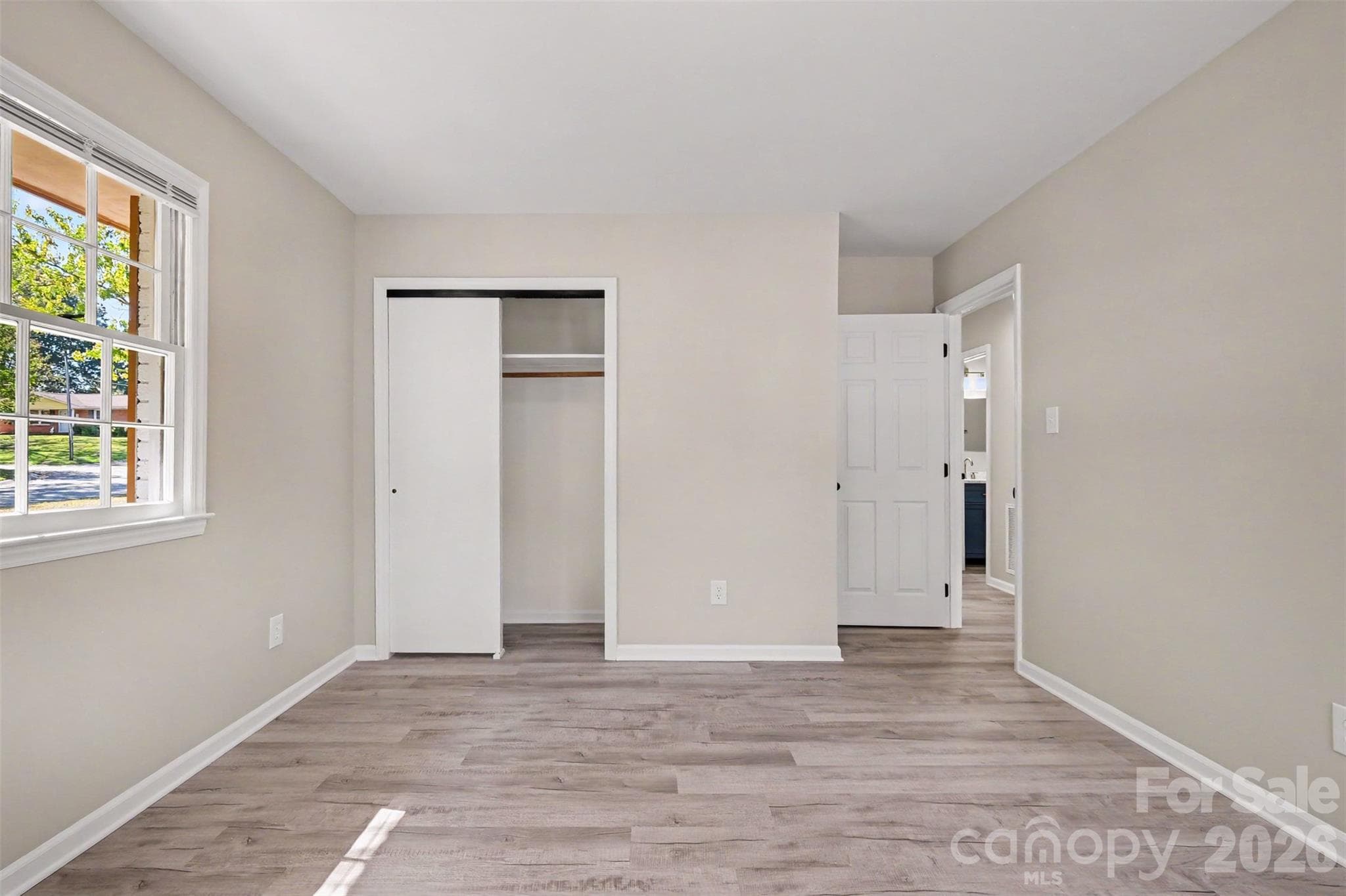 Spacious bedroom featuring a sliding door closet, fresh paint, and updated flooring throughout. - 3801 Hillock Court, Charlotte