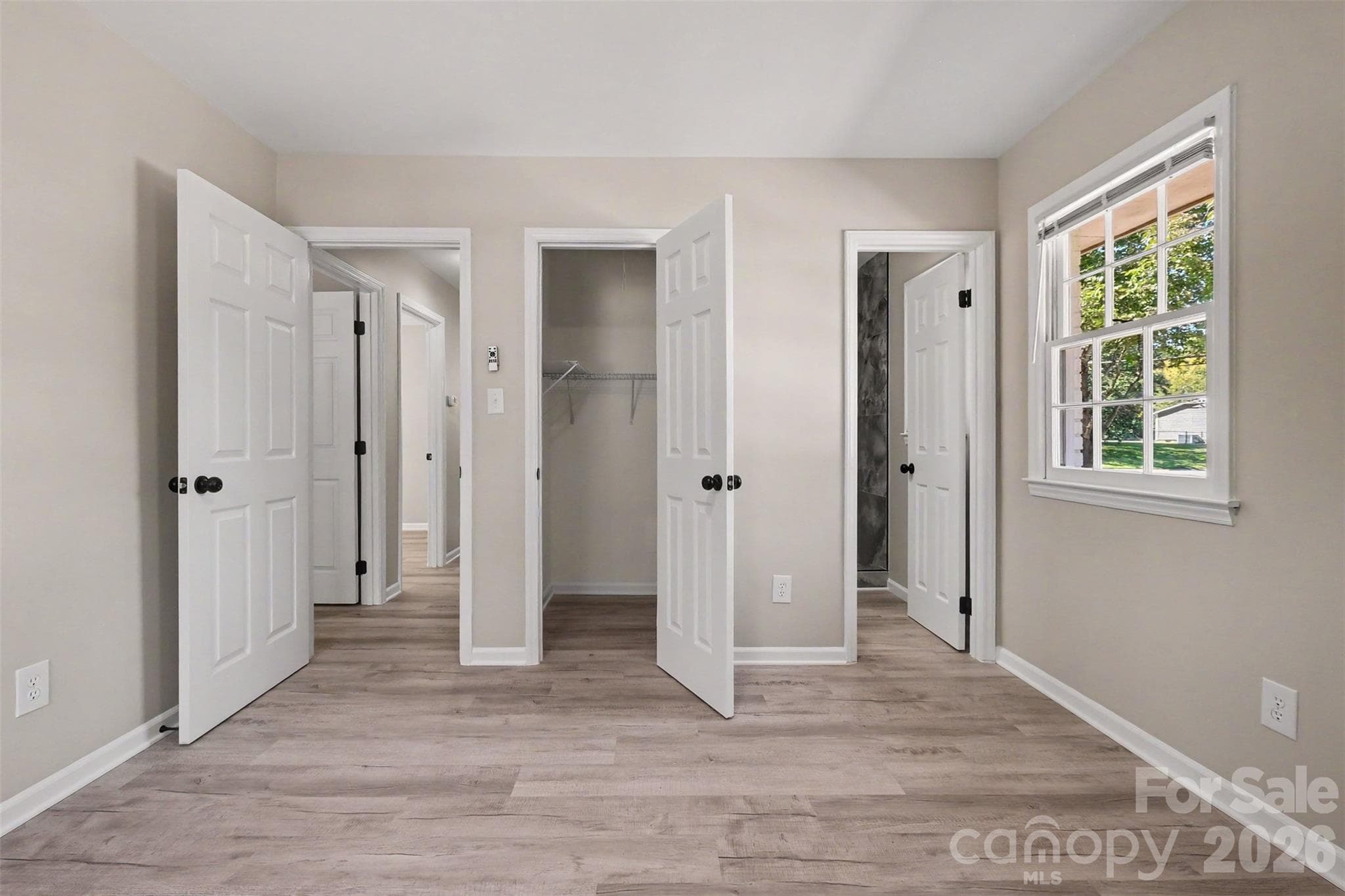 Primary bedroom featuring an open walk-in closet, fresh neutral paint, and direct access to the private ensuite bathroom. - 3801 Hillock Court, Charlotte