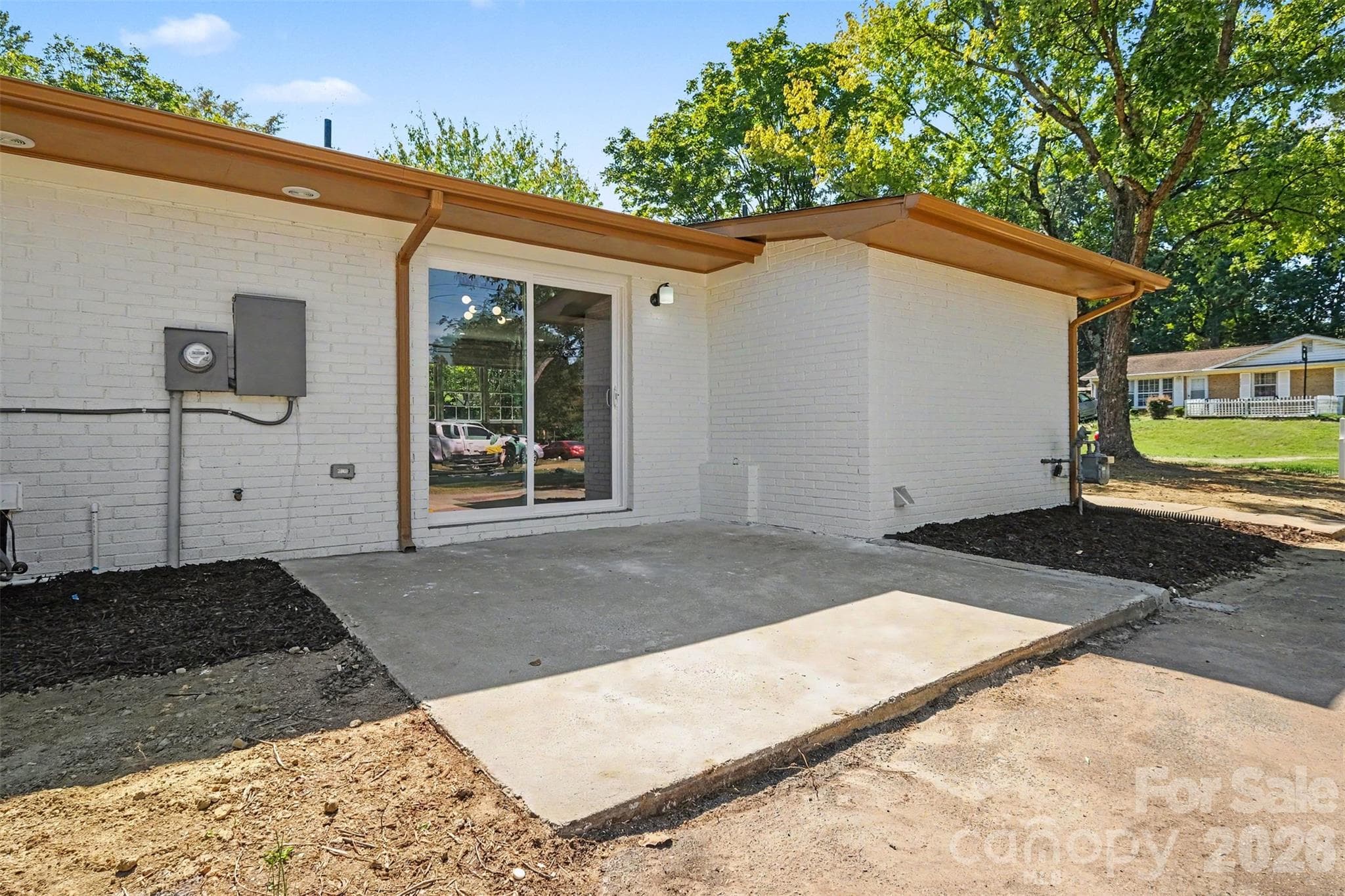 Outdoor patio space ideal for entertaining, showcasing new gutters, painted brick exterior, and direct sliding door access to the home. - 3801 Hillock Court, Charlotte