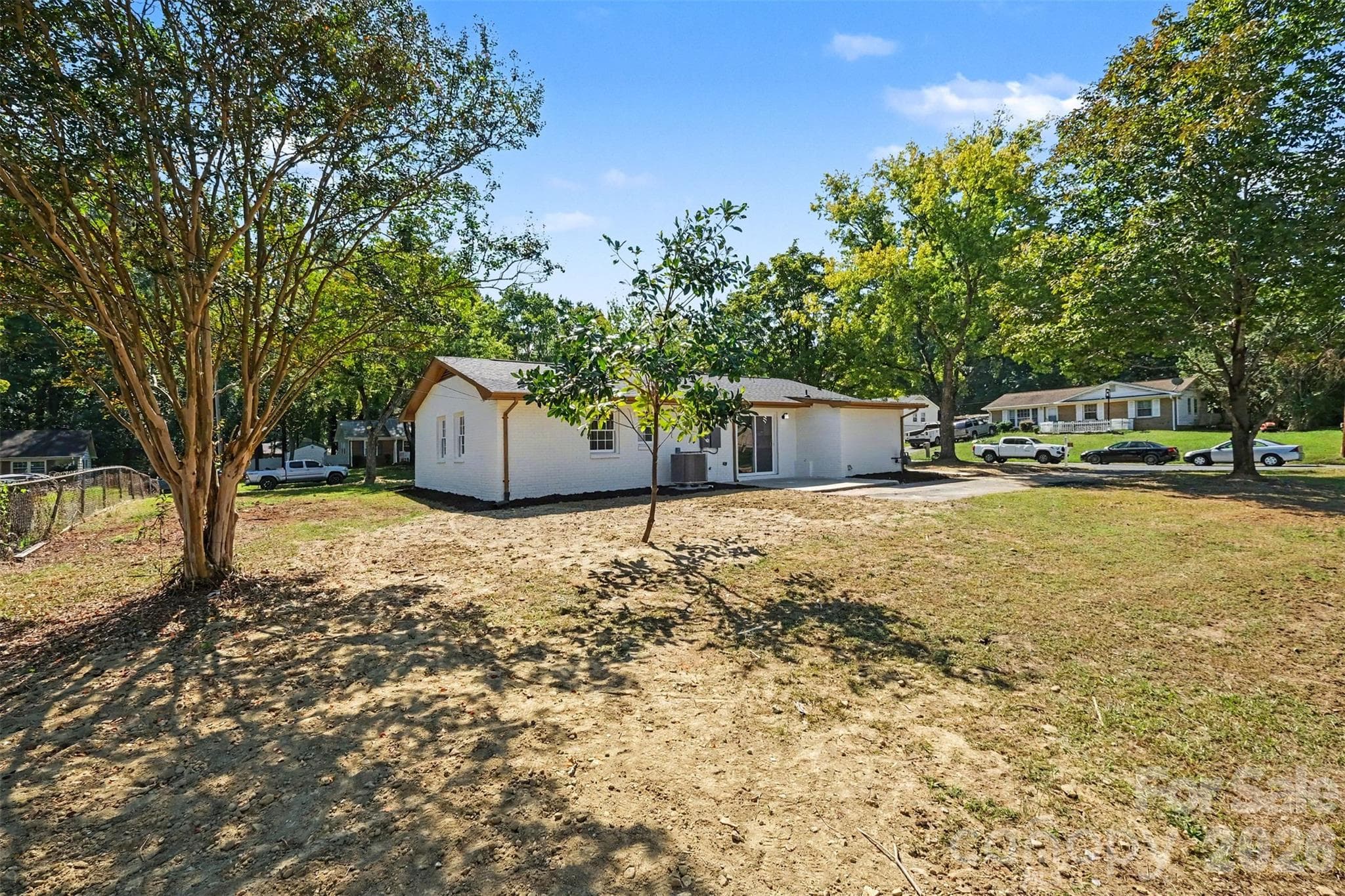 Spacious rear yard view from the property boundary, highlighting mature trees, open green space, and the back exterior of the home. - 3801 Hillock Court, Charlotte