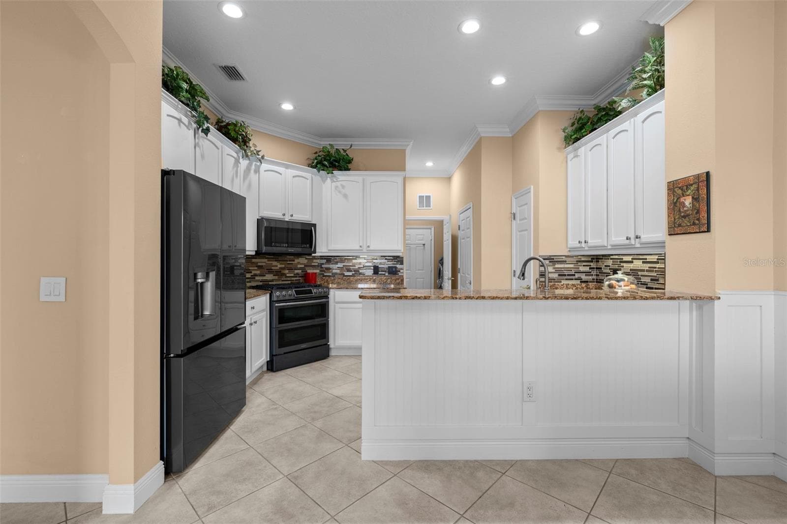 White cabinetry, granite countertops, and a generous breakfast bar make everyday meals and entertaining easy. - 8432 MIRAMAR WAY, LAKEWOOD RANCH