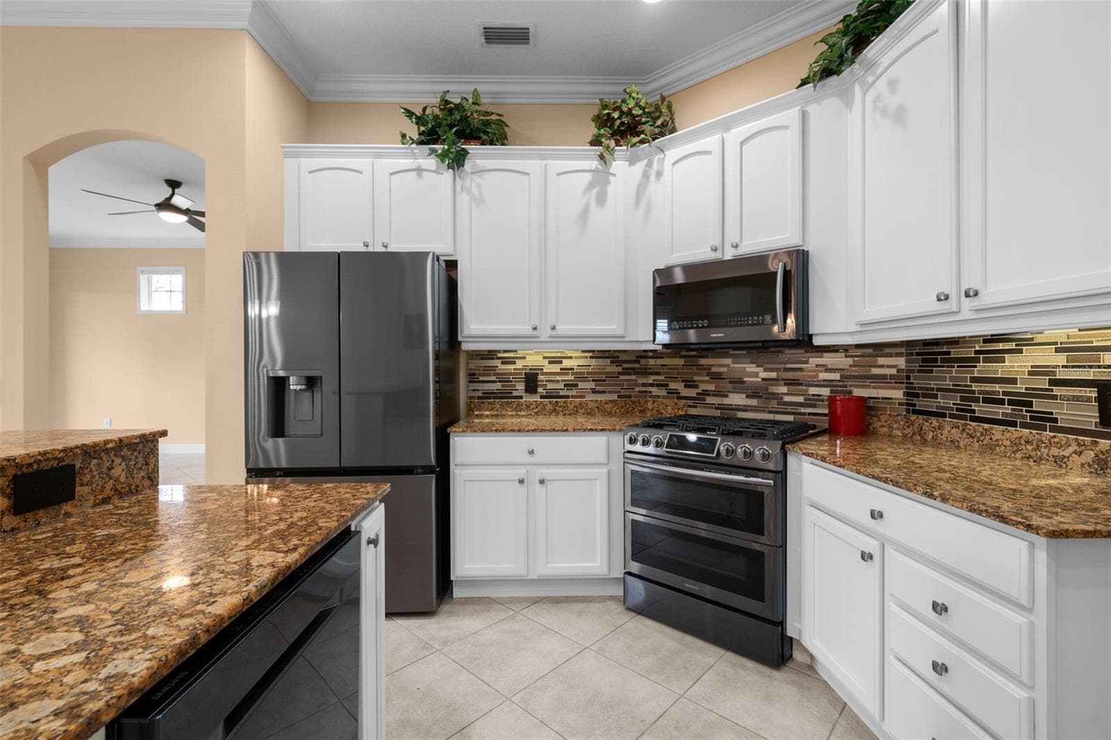 A gas range, decorative backsplash, and under-cabinet lighting bring style and function to meal prep. - 8432 MIRAMAR WAY, LAKEWOOD RANCH