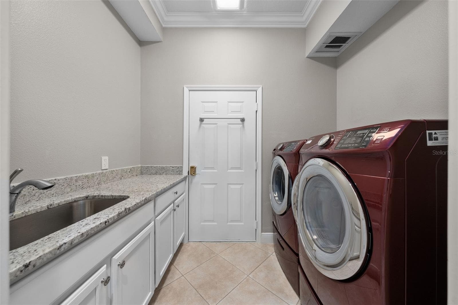 A spacious laundry room with front-load appliances, a utility sink, and plenty of counter and cabinet space. - 8432 MIRAMAR WAY, LAKEWOOD RANCH