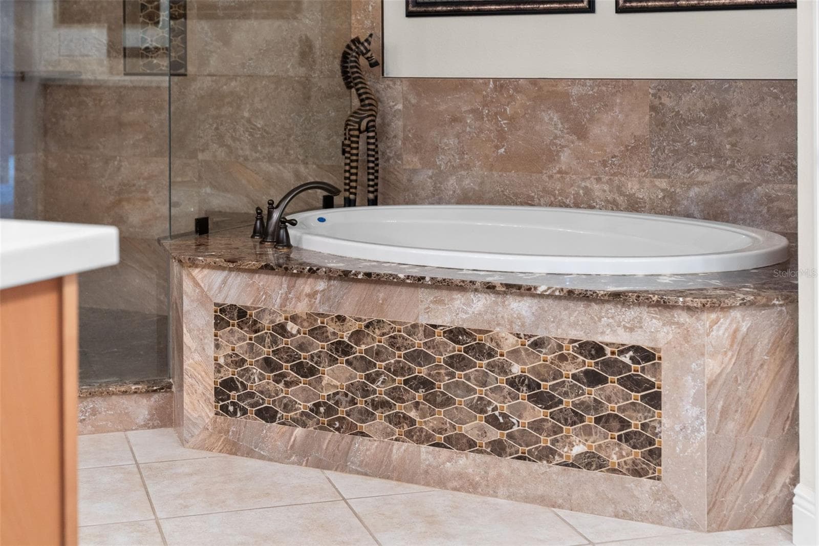 Unwind in the soaking tub, surrounded by rich stone finishes and decorative accents. - 8432 MIRAMAR WAY, LAKEWOOD RANCH