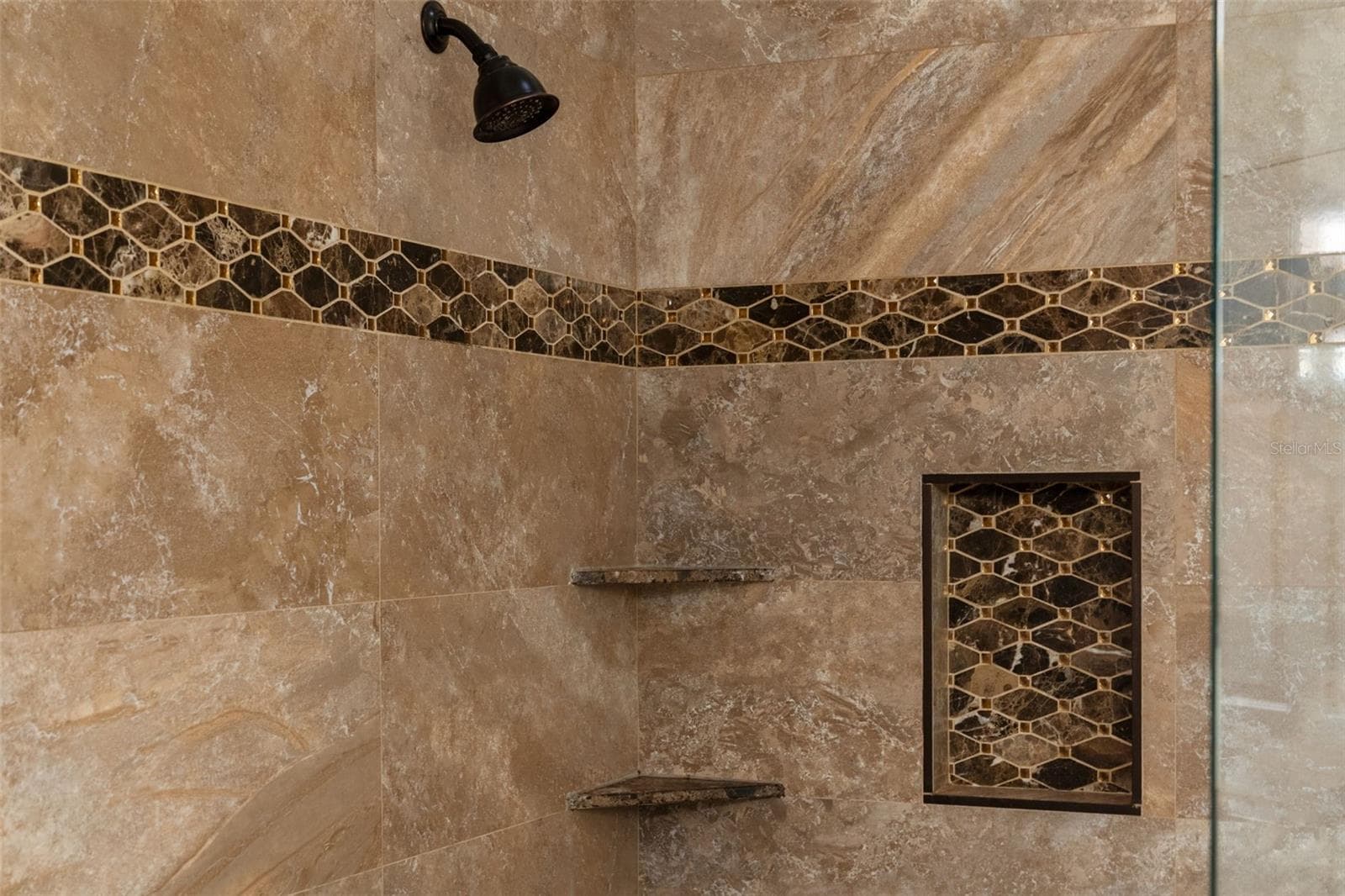 A generous shower with mosaic detailing, built-in shelves, and a recessed niche for everyday essentials. - 8432 MIRAMAR WAY, LAKEWOOD RANCH