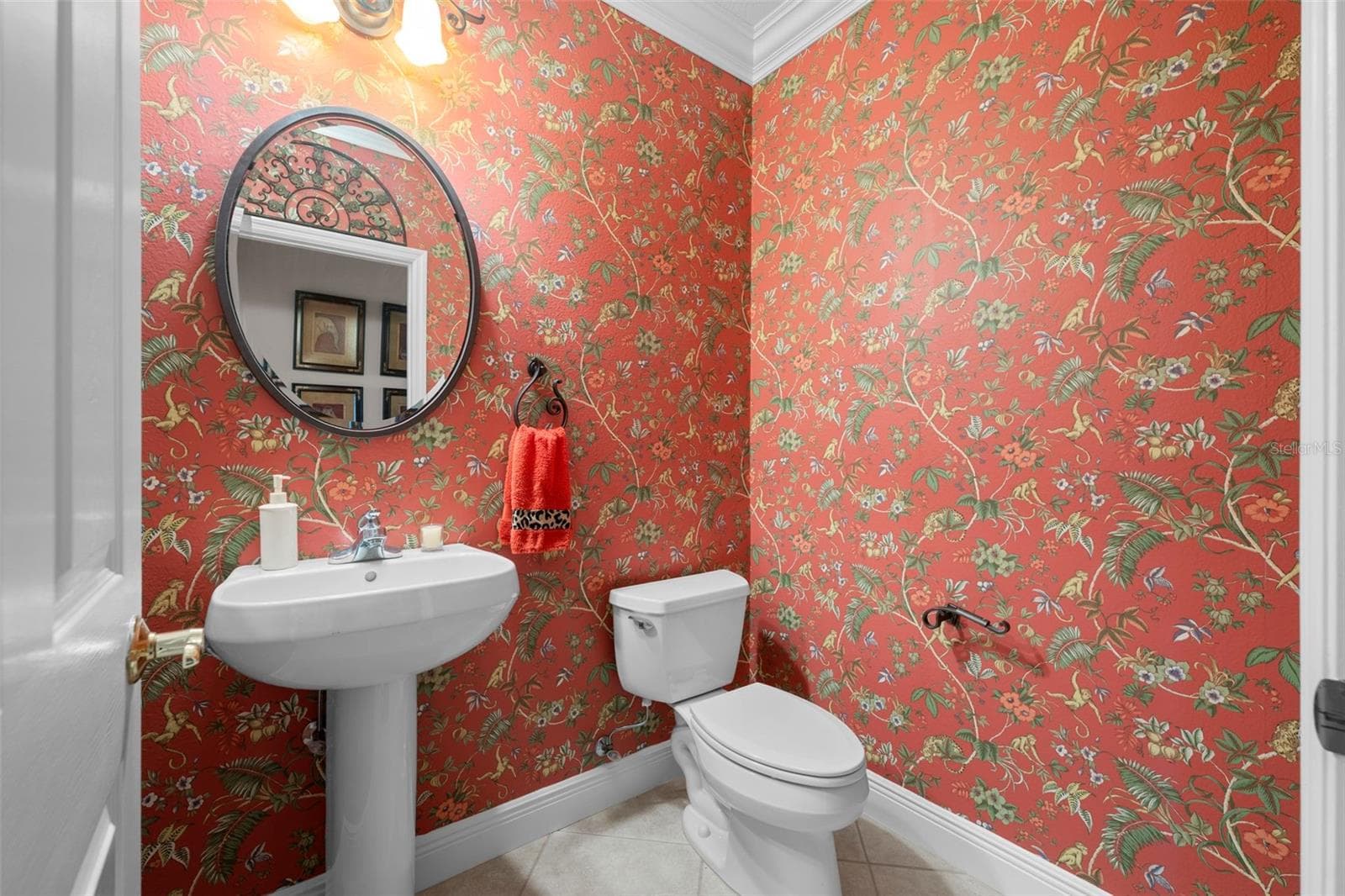 Cheerful patterned wallpaper and a classic pedestal sink bring personality to this bathroom. - 8432 MIRAMAR WAY, LAKEWOOD RANCH