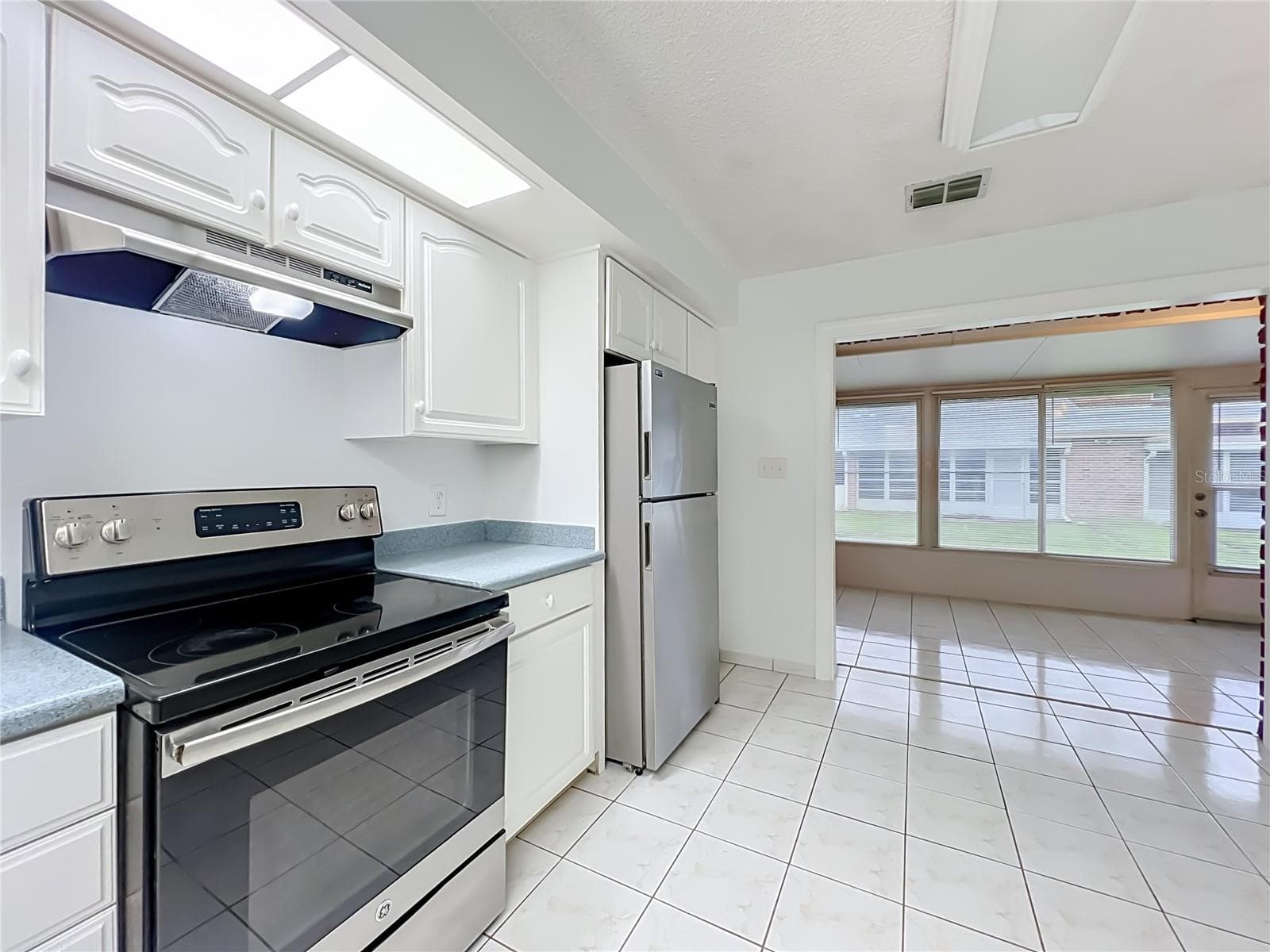 Bright kitchen with white cabinetry, ample storage and included appliances. - 1225 CARRIAGE LN #1, ORLANDO
