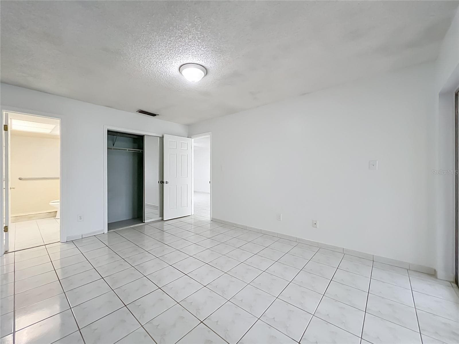 Spacious primary bedroom with ceramic tile flooring and plenty of room to make it your own. - 1225 CARRIAGE LN #1, ORLANDO