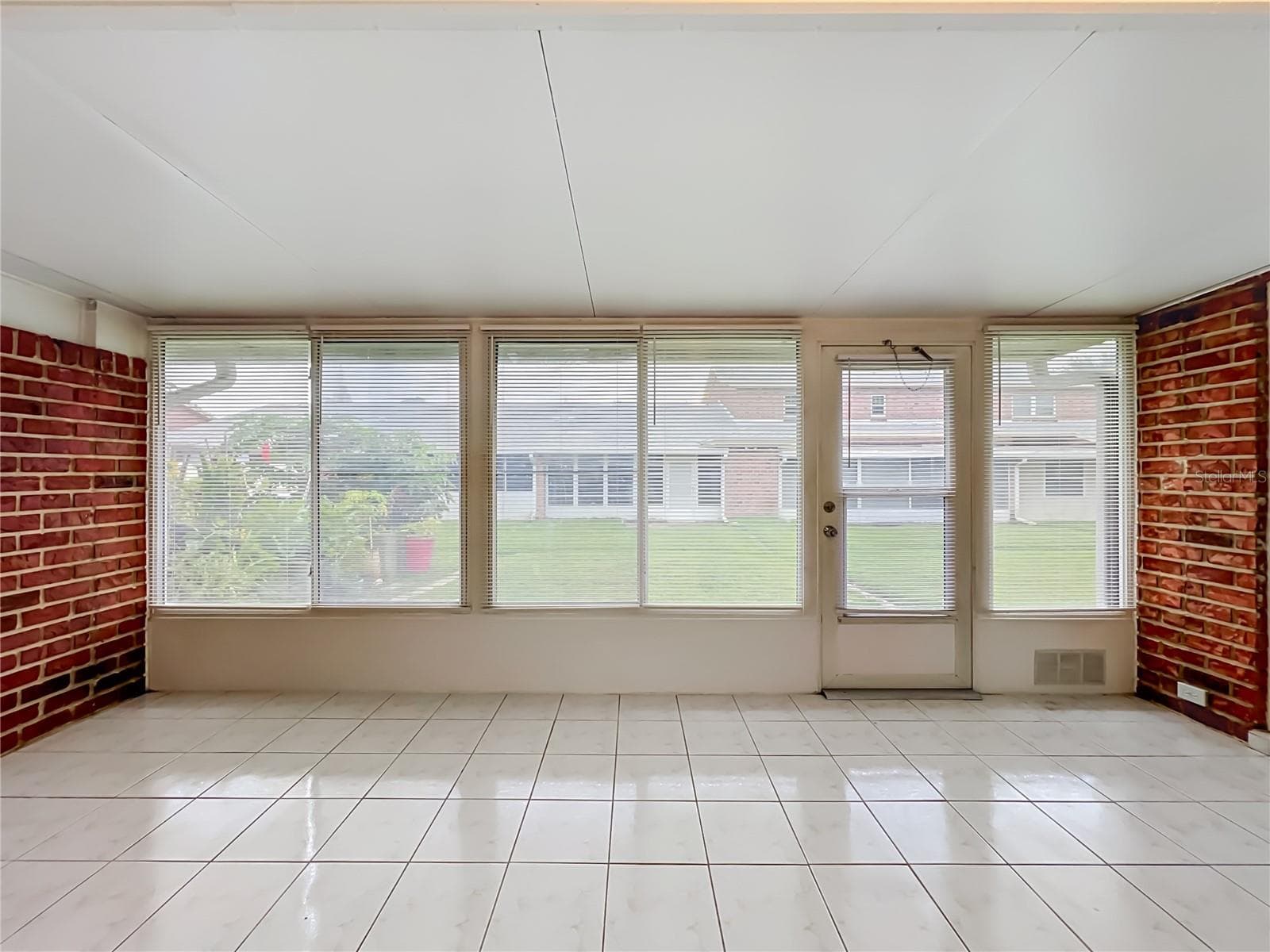 Spacious enclosed Florida room with tile flooring and wall-to-wall windows. - 1225 CARRIAGE LN #1, ORLANDO