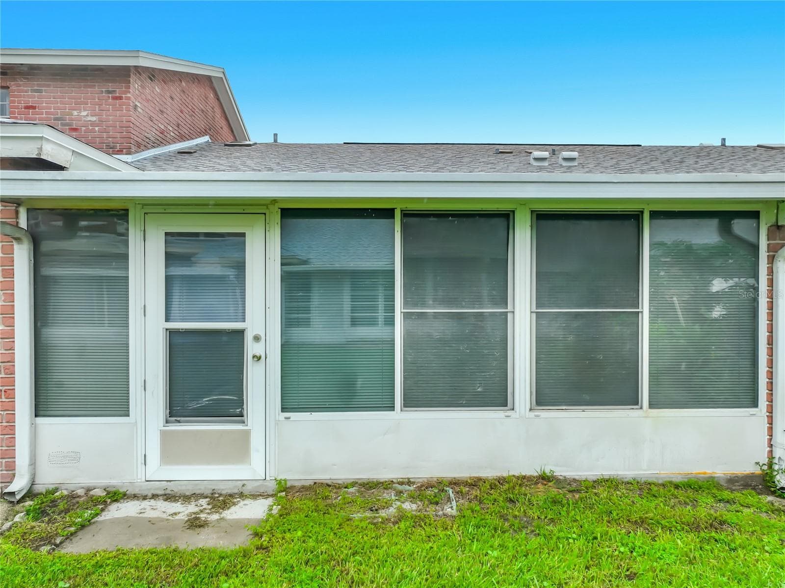 Exterior view showcasing the home's large enclosed Florida room. - 1225 CARRIAGE LN #1, ORLANDO