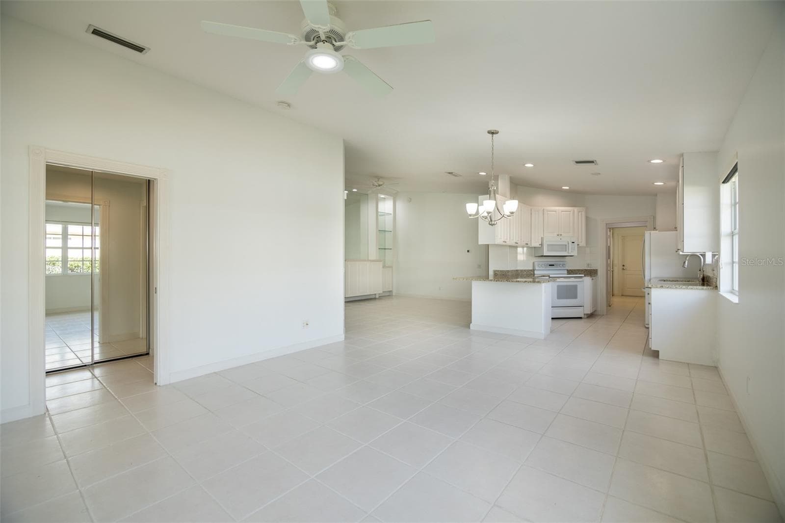 Dining and or living room with views to the kitchen and formal living room as well as the primary suite. - 8876 ESTEPONA CT, SARASOTA
