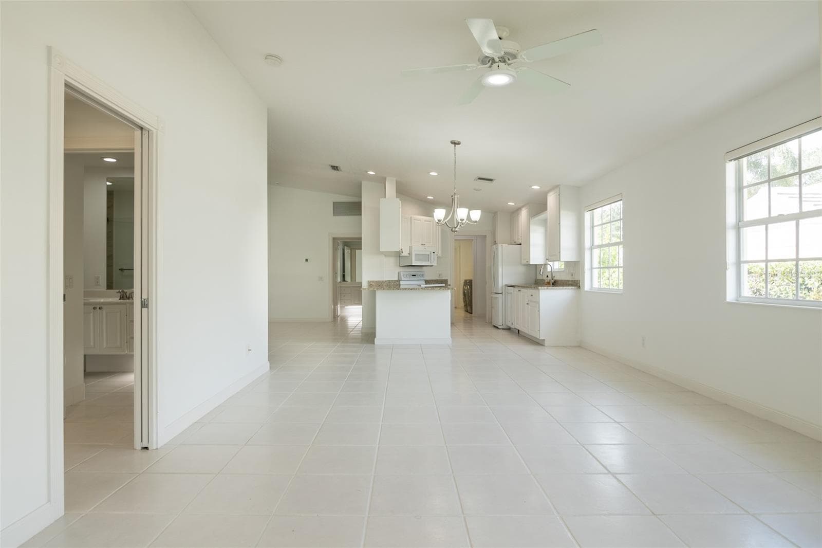 Dining and or living room with views to the kitchen and formal living room as well as the primary suite. - 8876 ESTEPONA CT, SARASOTA