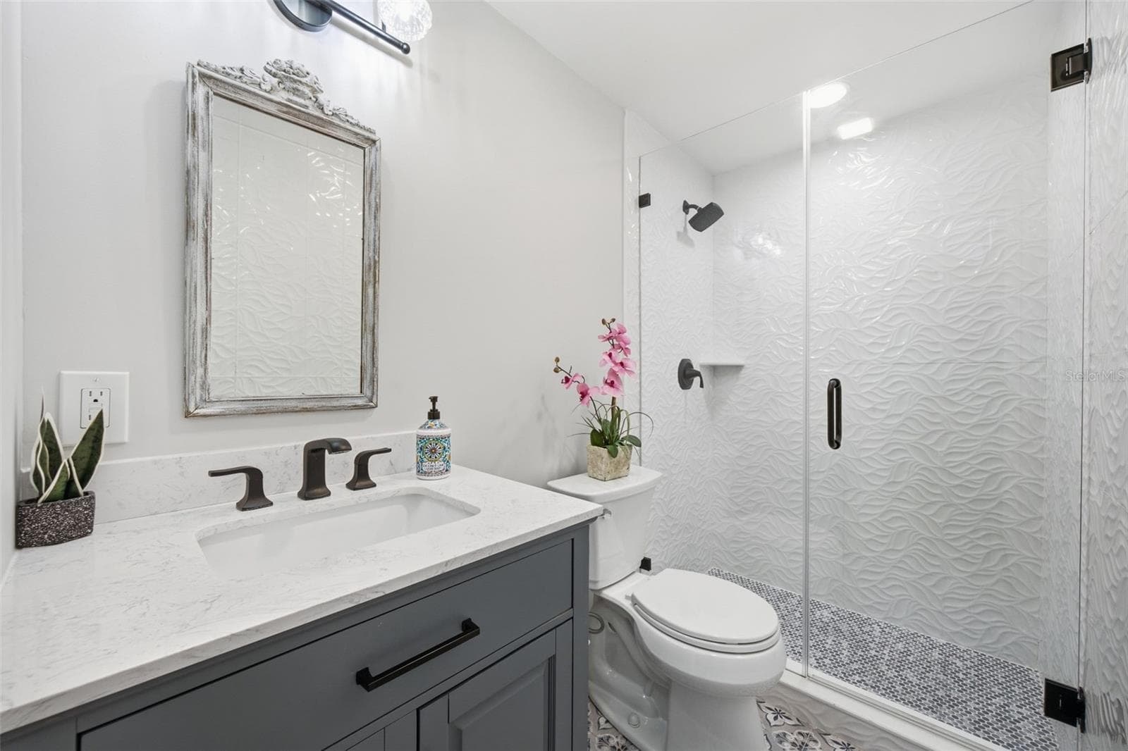 Beautifully updated main bath featuring sculptural 3D wave tile, frameless glass shower. - 5837 TENNESSEE AVE, NEW PORT RICHEY