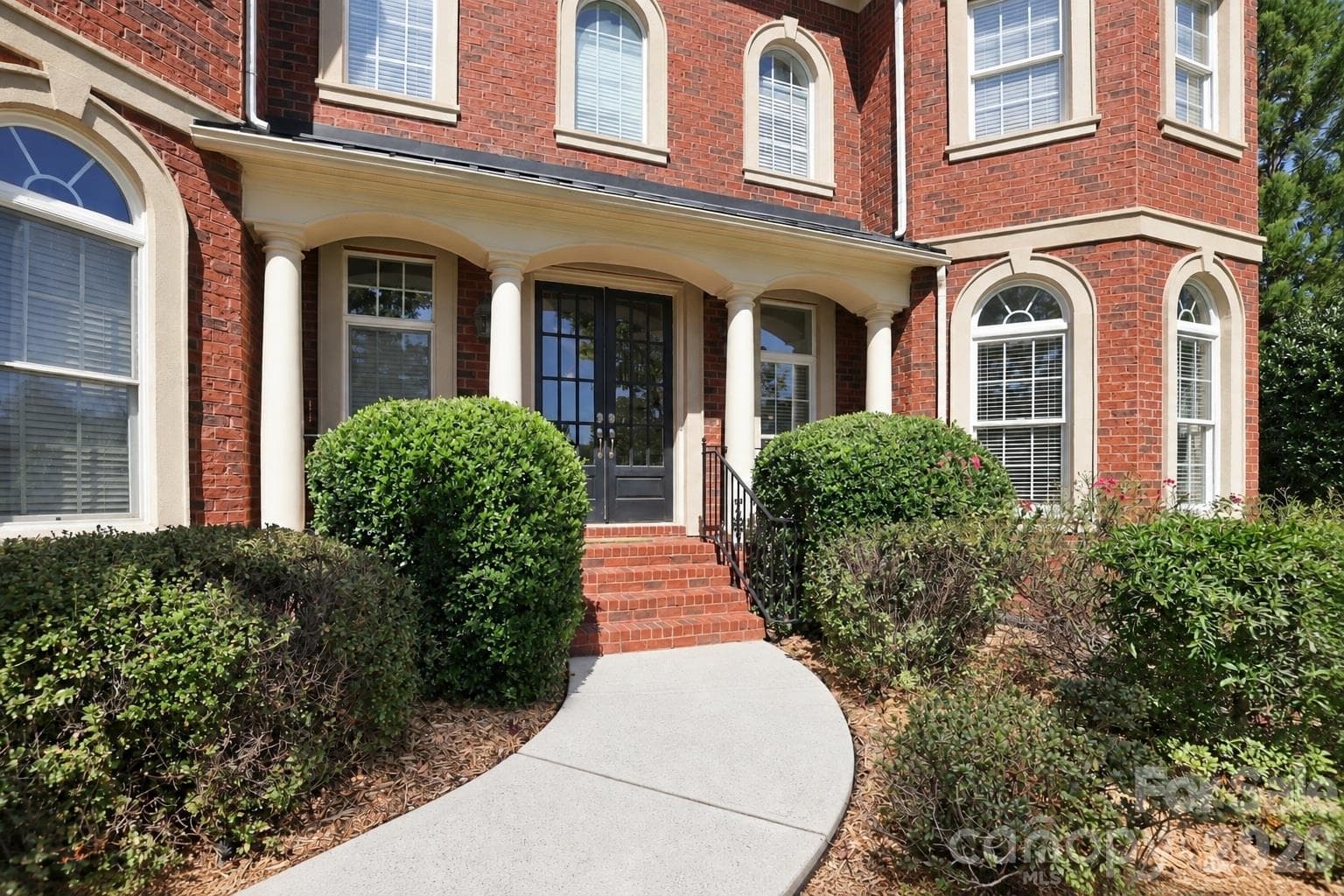 Arched windows, contrasting stone-toned trim and handsome brickwork give this home architectural character well beyond the ordinary. - 2309 Highland Forest Drive, Waxhaw