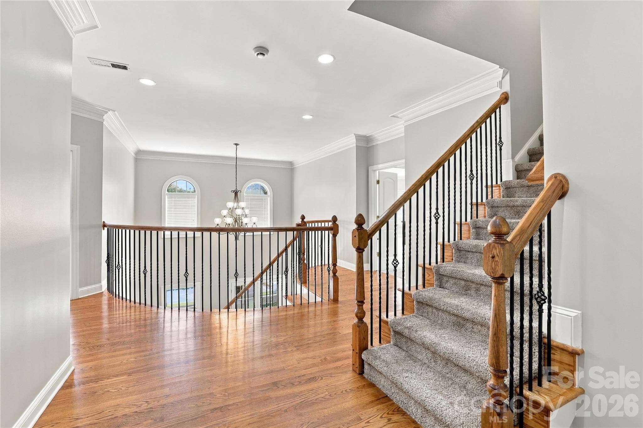 The second-floor landing continues the home’s impressive architectural style, with hardwood floors, detailed iron balusters and an open overlook to the foyer below. Its generous width gives the upstairs a spacious feel rather than simply serving as a hallway between bedrooms. - 2309 Highland Forest Drive, Waxhaw