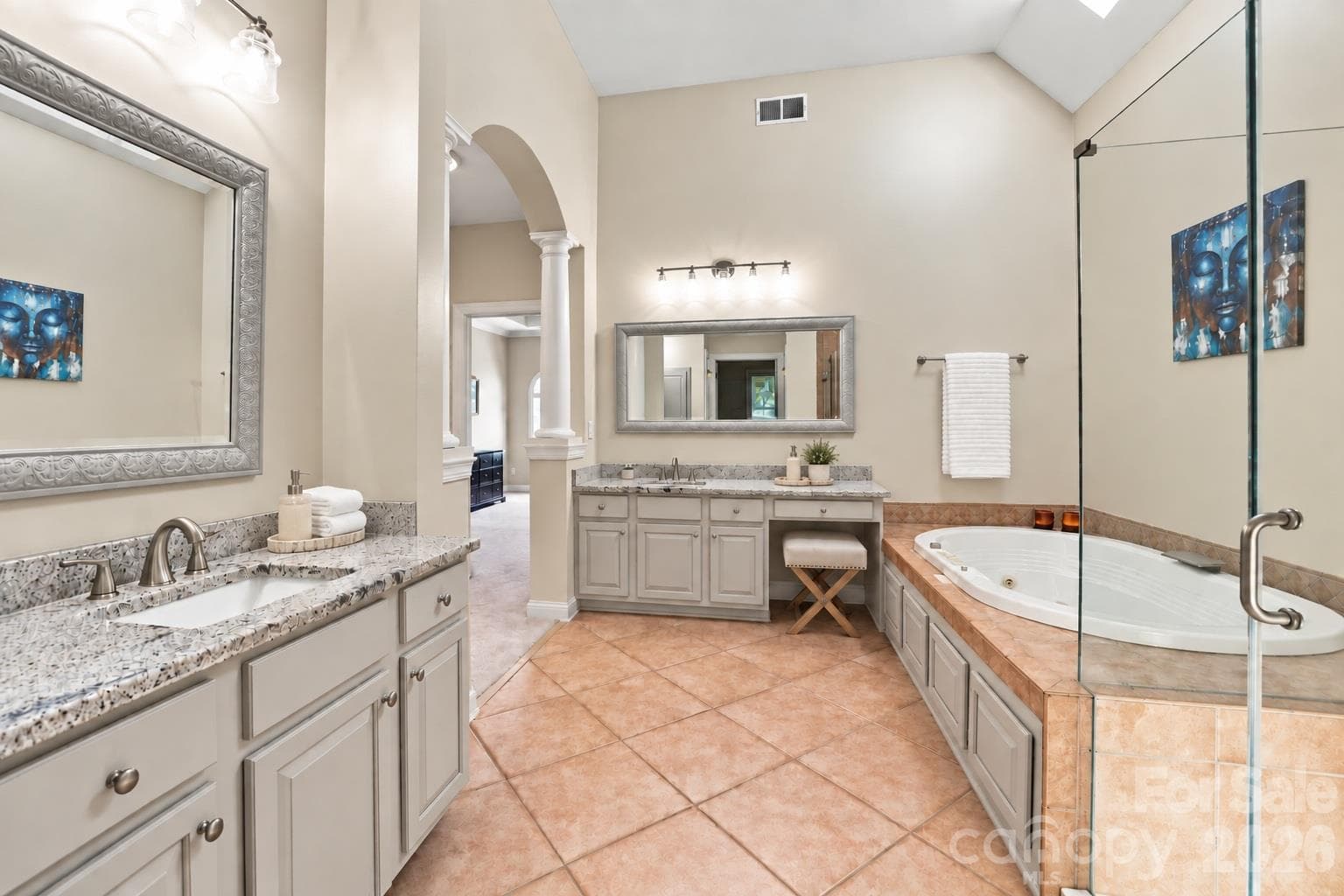 The high ceiling, skylight and arched opening with columns give this bathroom architectural interest beyond its generous size. Separate granite-topped vanity areas on opposite sides of the room, including a seated vanity, provide abundant counter and storage space. - 2309 Highland Forest Drive, Waxhaw