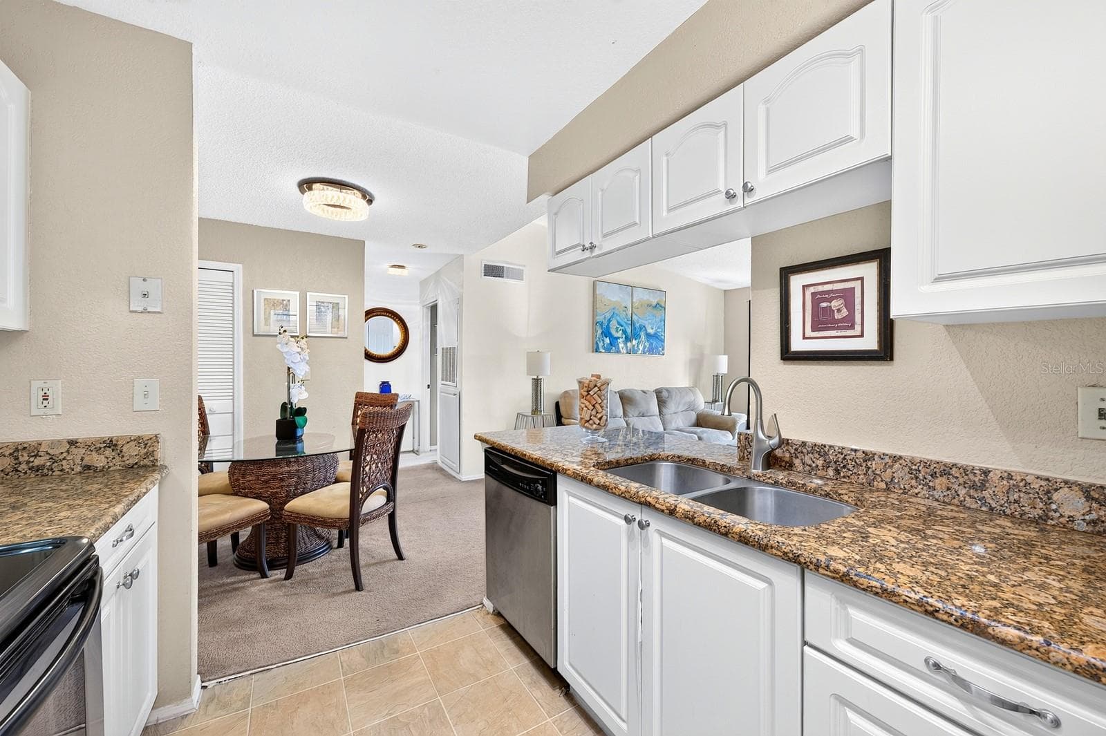 The Kitchen features STONE COUNTERTOPS, beautiful white cabinetry, STAINLESS STEEL APPLIANCES and a convenient breakfast bar, overlooking the Living Room and Dining Area. - 2550 N ALAFAYA TRL #6303, ORLANDO
