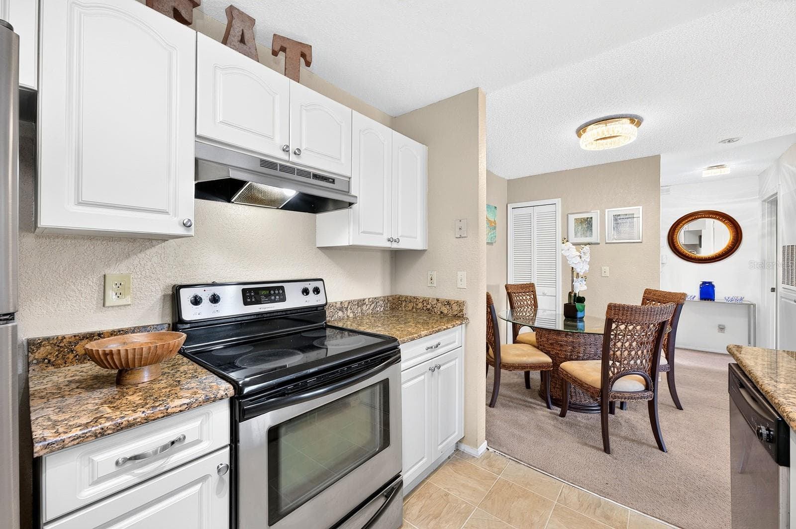 The Kitchen features STONE COUNTERTOPS, beautiful white cabinetry, STAINLESS STEEL APPLIANCES and a convenient breakfast bar, overlooking the Living Room and Dining Area. - 2550 N ALAFAYA TRL #6303, ORLANDO