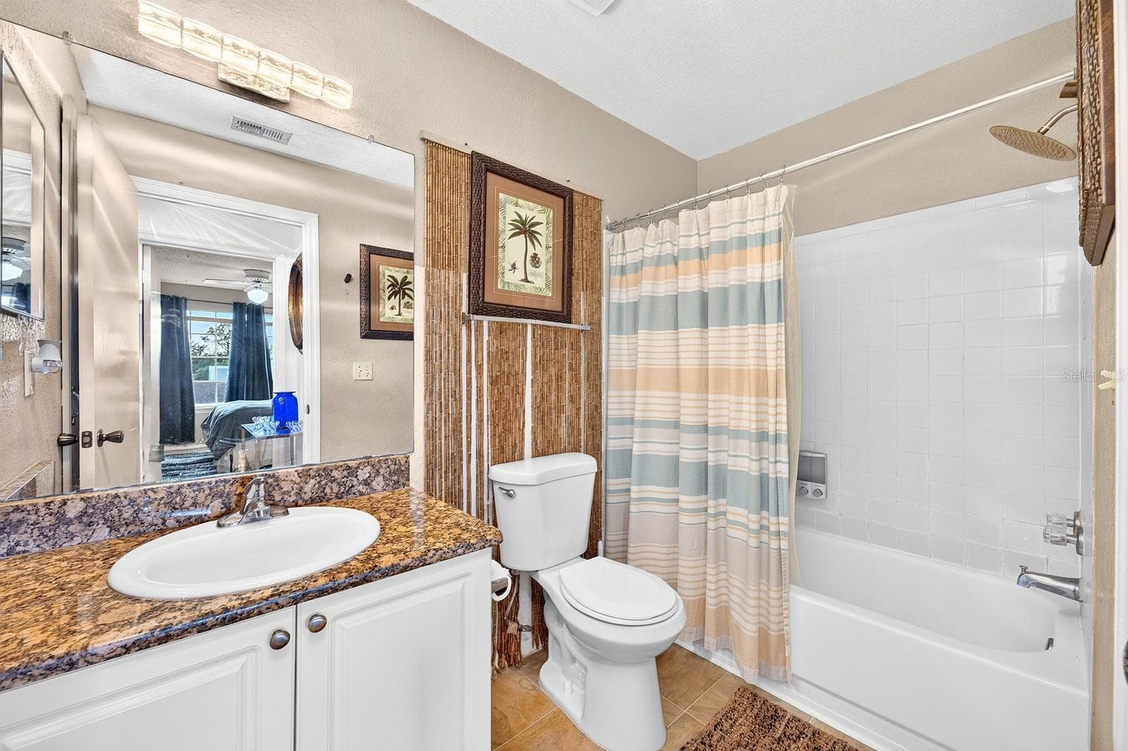 The nearby Bathroom features a stone countertop and tub/shower combination with a RAINFALL SHOWER HEAD. - 2550 N ALAFAYA TRL #6303, ORLANDO