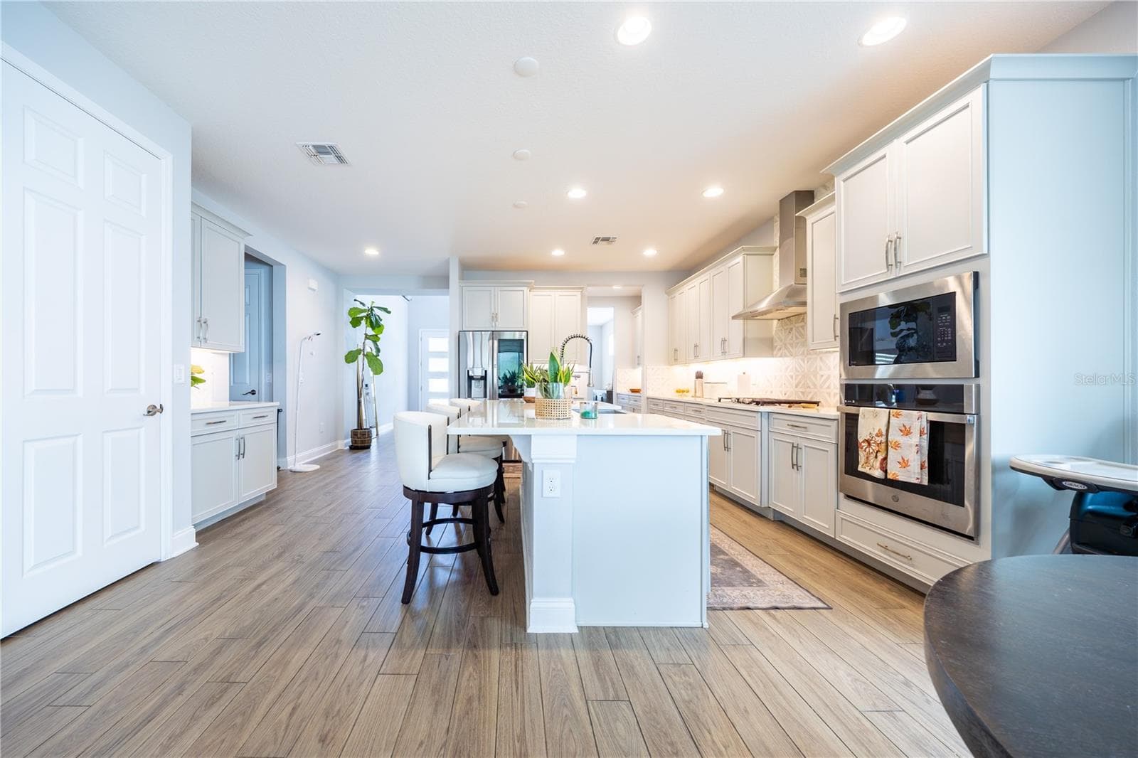 Elegant kitchen with white cabinetry, a spacious island with seating, and stainless steel appliances. - 1316 SOUTHERN SUN DRIVE, OAKLAND