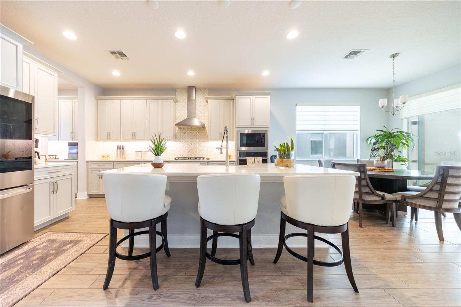 Spacious kitchen island with seating for three, complemented by white cabinetry and a decorative tile backsplash. - 1316 SOUTHERN SUN DRIVE, OAKLAND