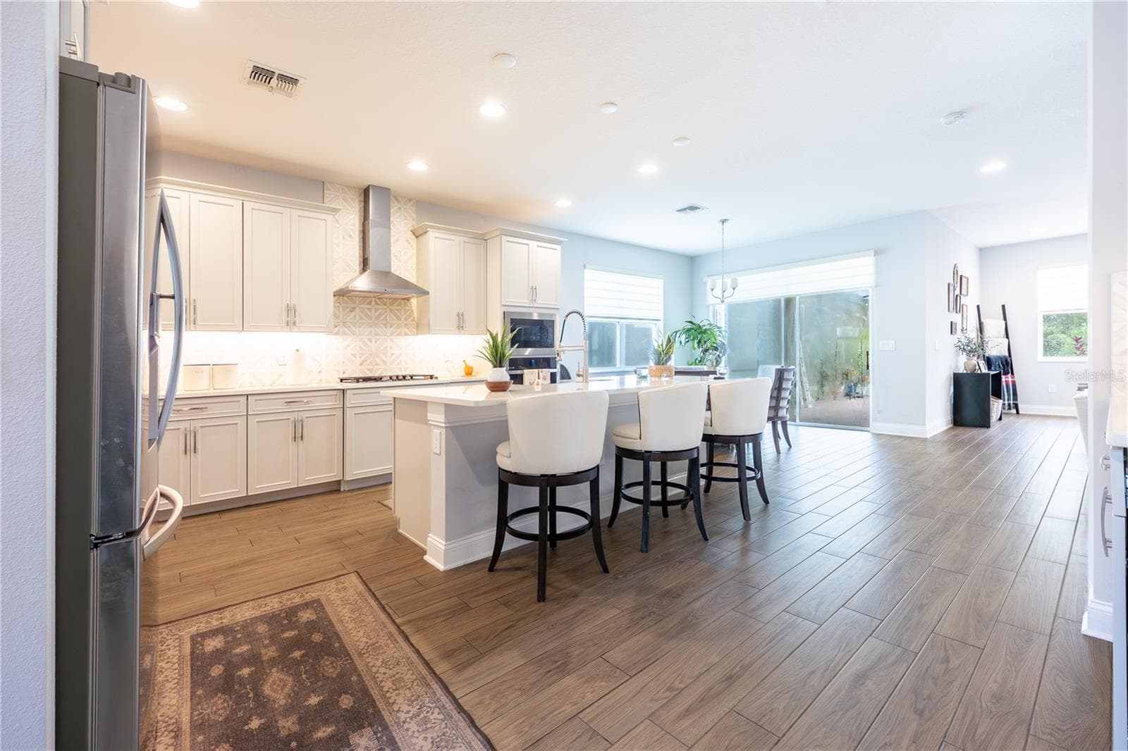Open-concept kitchen with a generous island, stainless steel range hood, and easy access to the covered patio. - 1316 SOUTHERN SUN DRIVE, OAKLAND