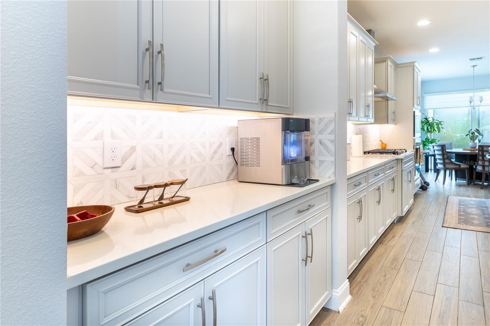 Stylish serving area with white cabinetry, geometric tile backsplash, and under-cabinet lighting. - 1316 SOUTHERN SUN DRIVE, OAKLAND