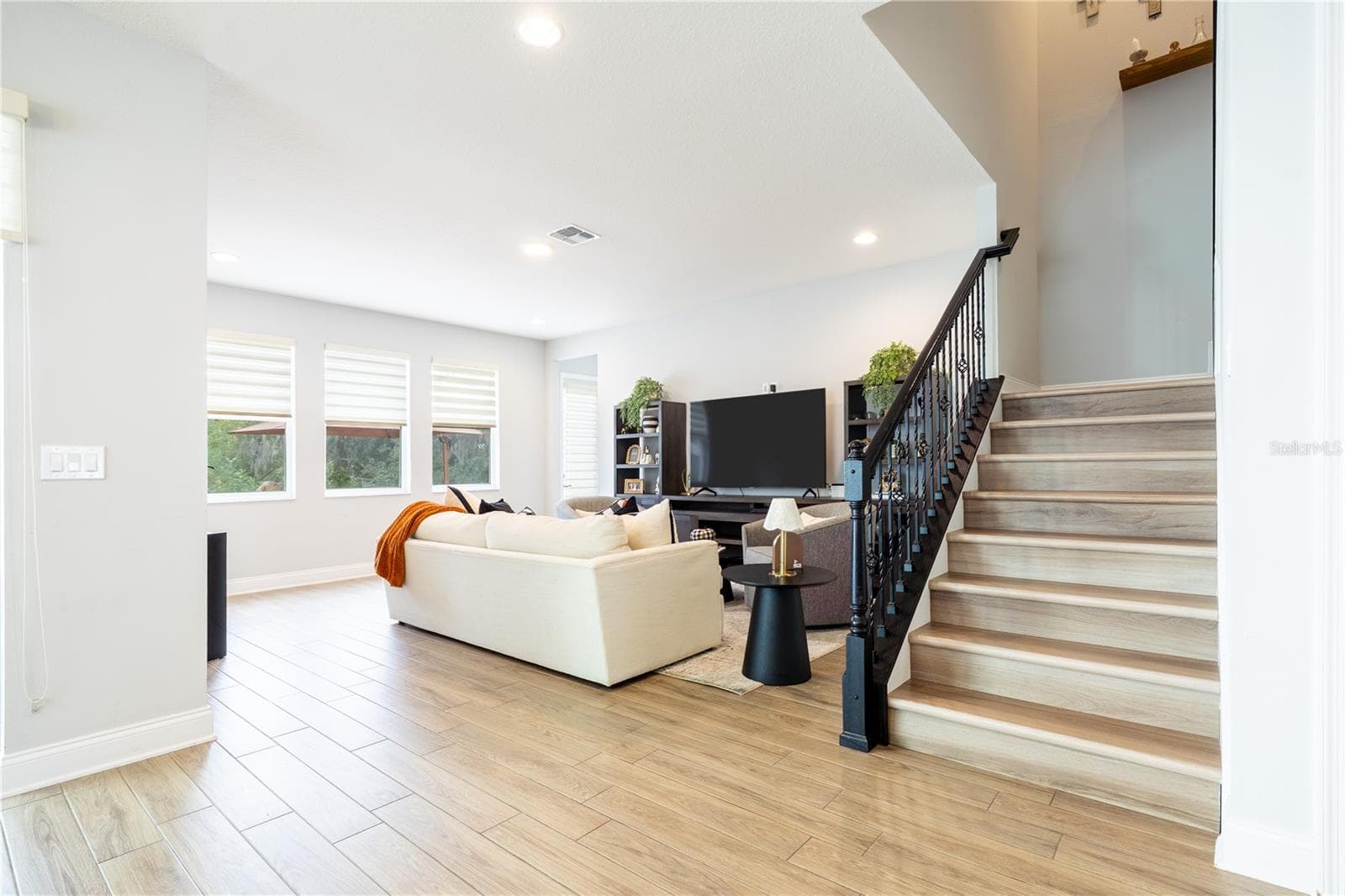 Elegant staircase with decorative metal railings beside an inviting living room with garden views. - 1316 SOUTHERN SUN DRIVE, OAKLAND