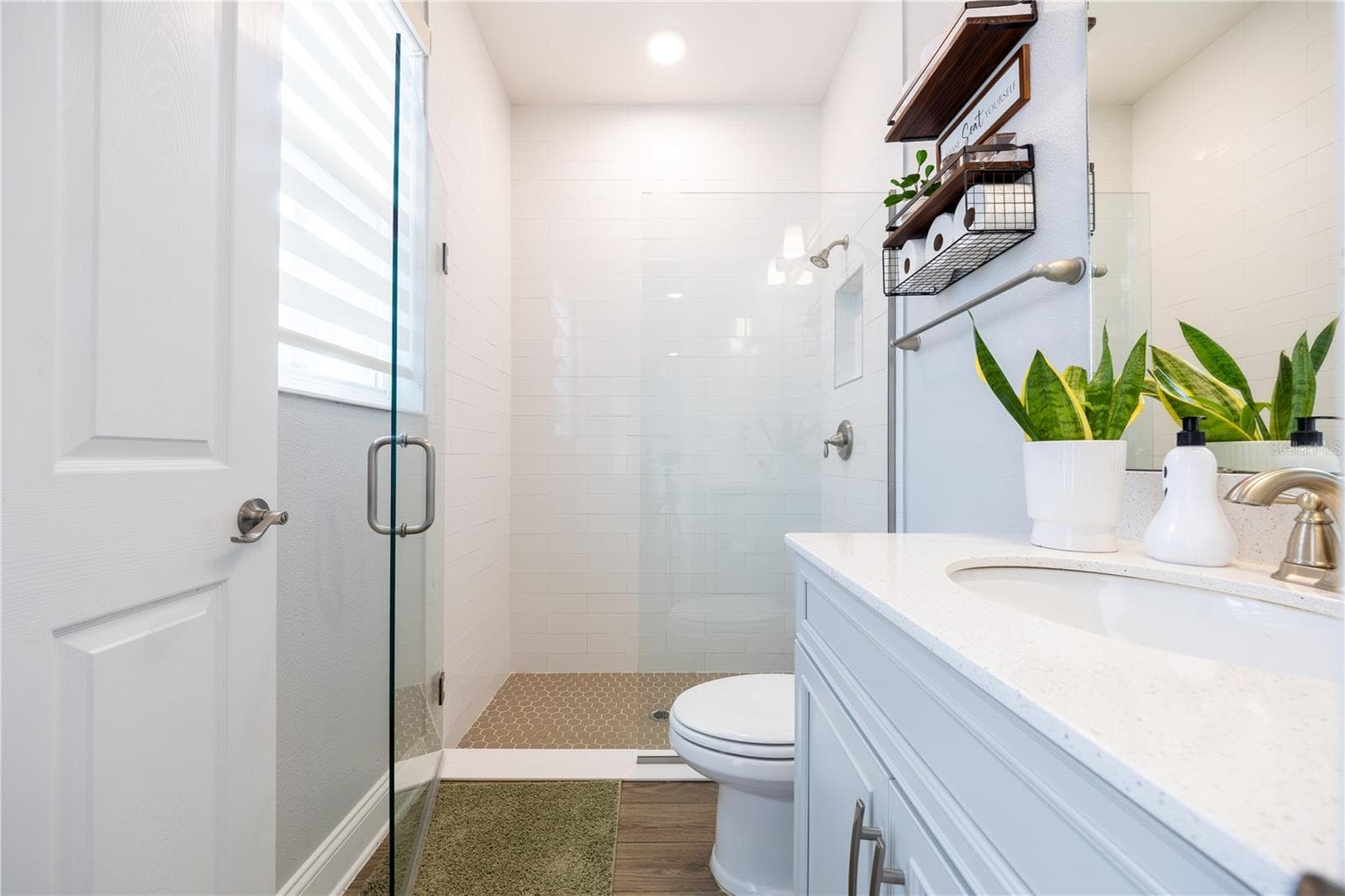 Bright bathroom featuring a frameless glass shower, white tile walls, mosaic shower floor, and a spacious vanity countertop. - 1316 SOUTHERN SUN DRIVE, OAKLAND