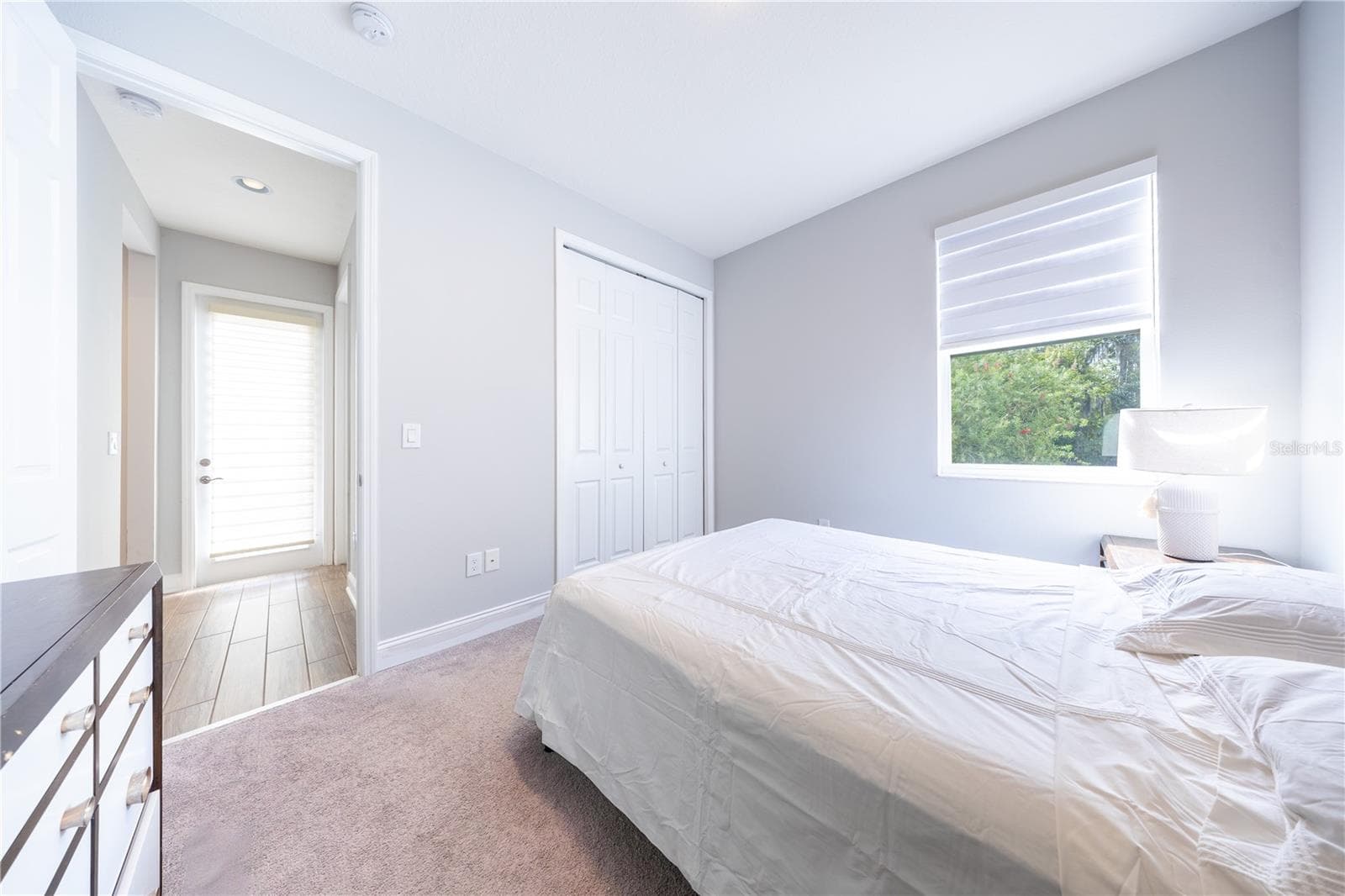 Bedroom with soft neutral tones, carpet flooring, a closet with folding doors, and a window overlooking greenery. - 1316 SOUTHERN SUN DRIVE, OAKLAND