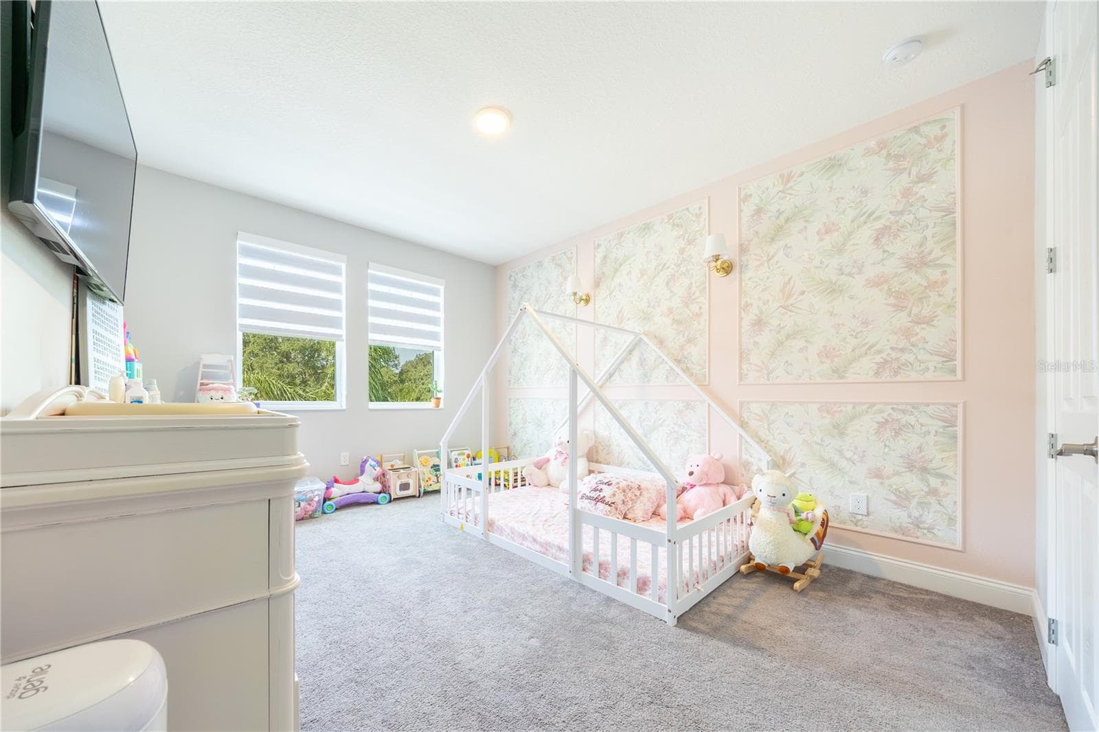 Charming bedroom with a floral accent wall, decorative sconces, and windows with lake views. - 1316 SOUTHERN SUN DRIVE, OAKLAND
