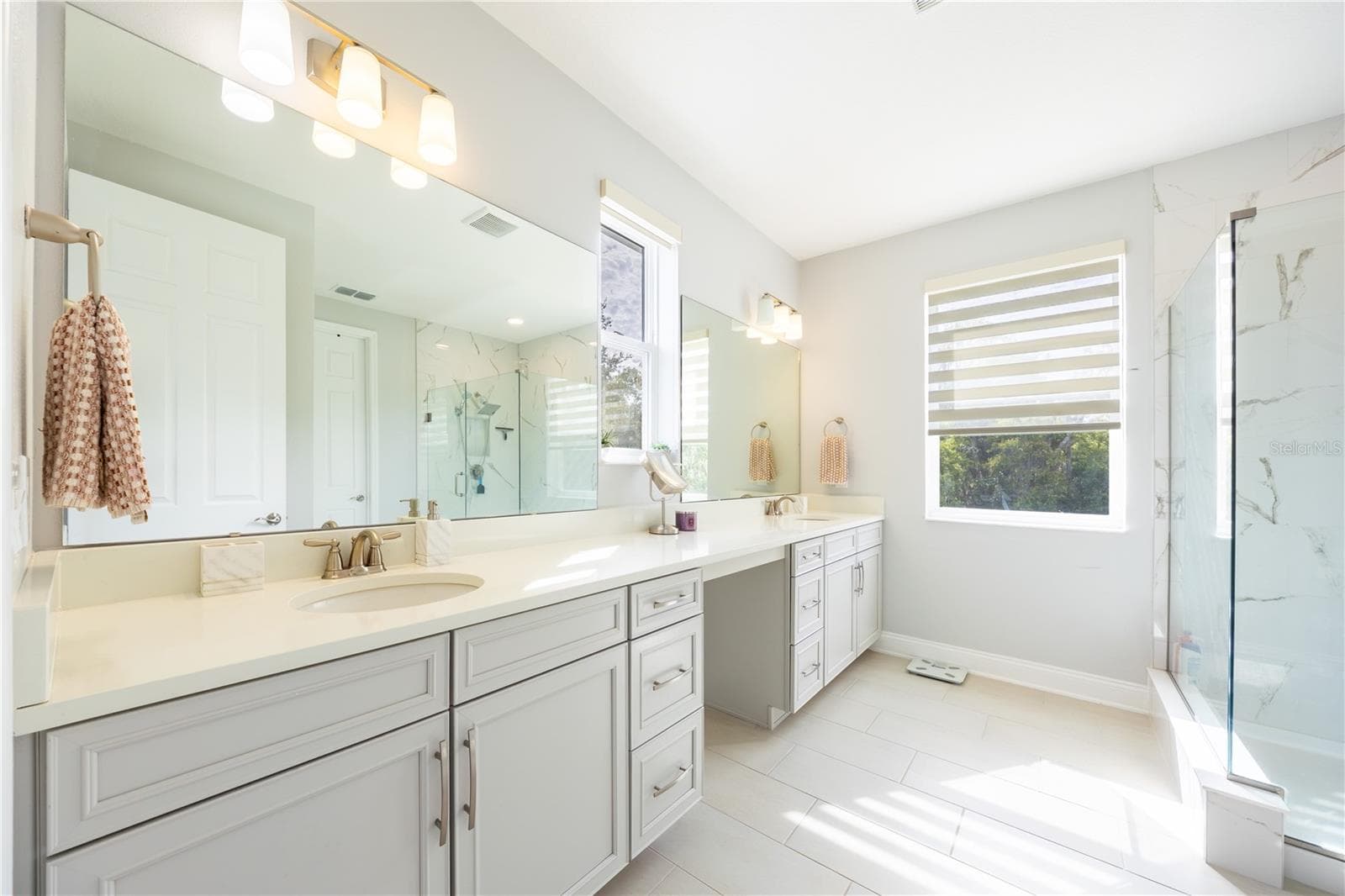 Elegant bathroom with a dual-sink vanity, dressing area, and glass-enclosed shower. - 1316 SOUTHERN SUN DRIVE, OAKLAND