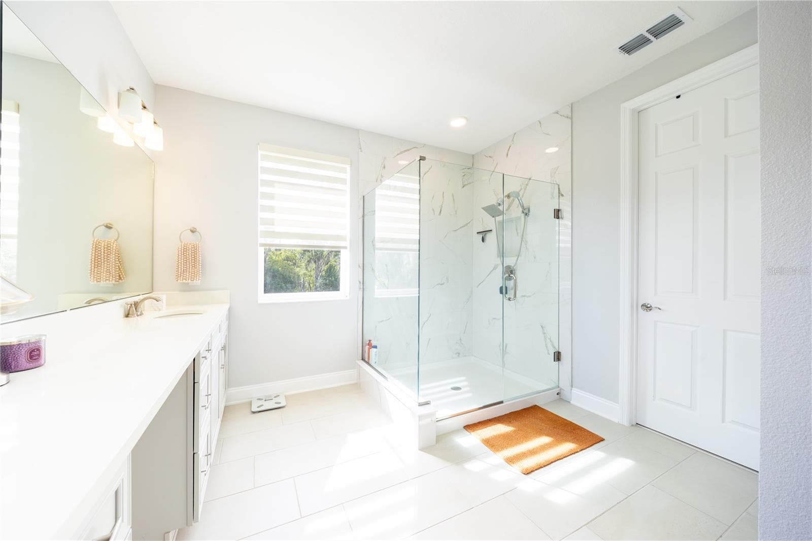 Refined primary bathroom with a frameless glass shower and marble-look tile finishes. - 1316 SOUTHERN SUN DRIVE, OAKLAND