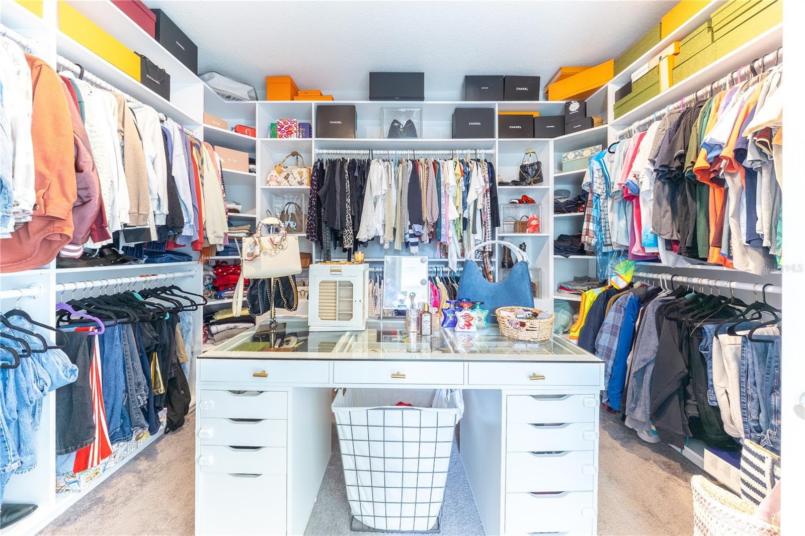 Expansive custom walk-in closet with built-in shelving, double hanging rods, and a central glass-top storage island. - 1316 SOUTHERN SUN DRIVE, OAKLAND