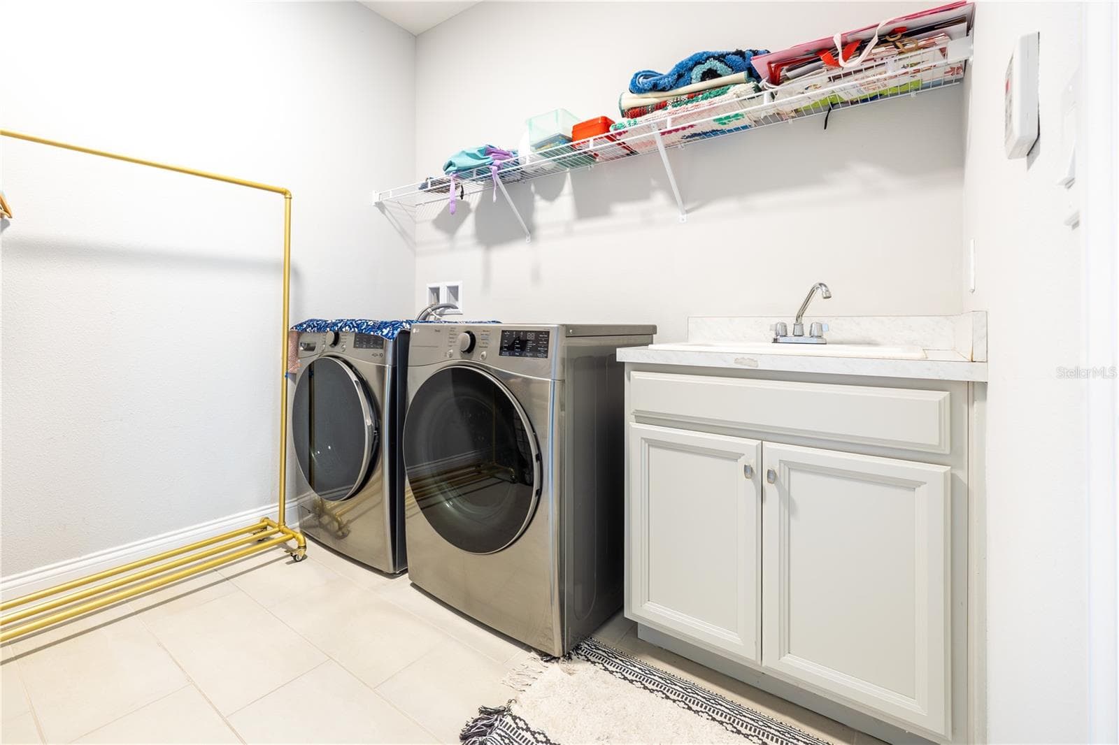 Laundry room with included front-load washer and dryer, utility sink, and storage shelving. - 1316 SOUTHERN SUN DRIVE, OAKLAND