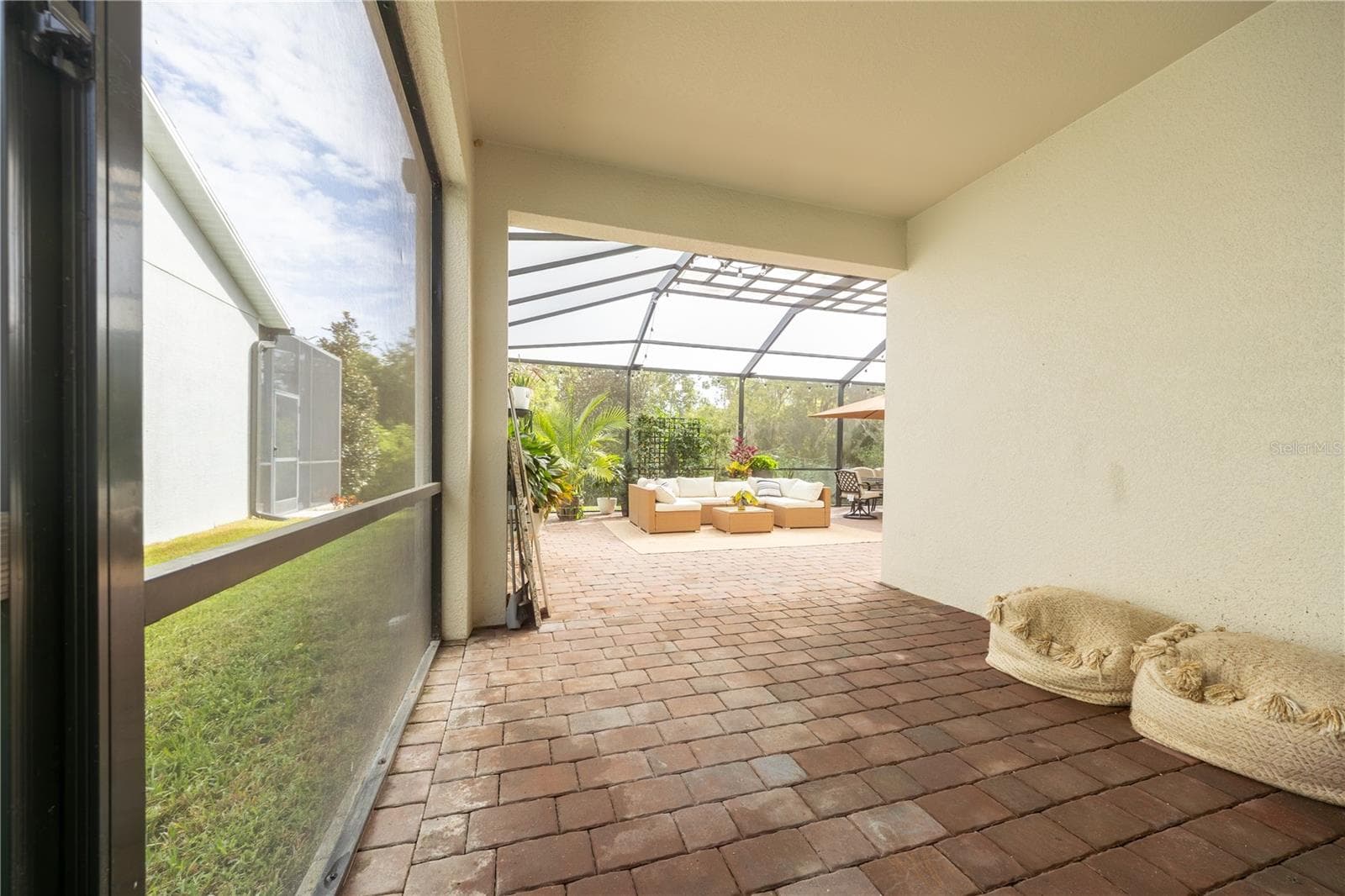Covered lanai with paver flooring opening to an expansive screened patio with lounge and dining areas. - 1316 SOUTHERN SUN DRIVE, OAKLAND