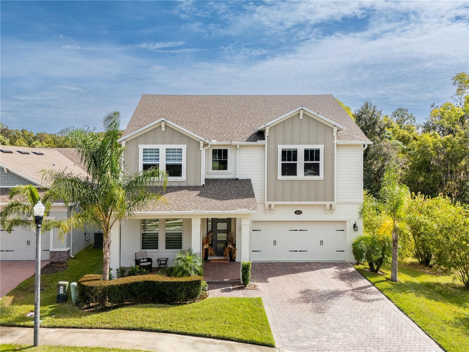 Elevated front view of the two-story home with tropical landscaping and a paver driveway. - 1316 SOUTHERN SUN DRIVE, OAKLAND