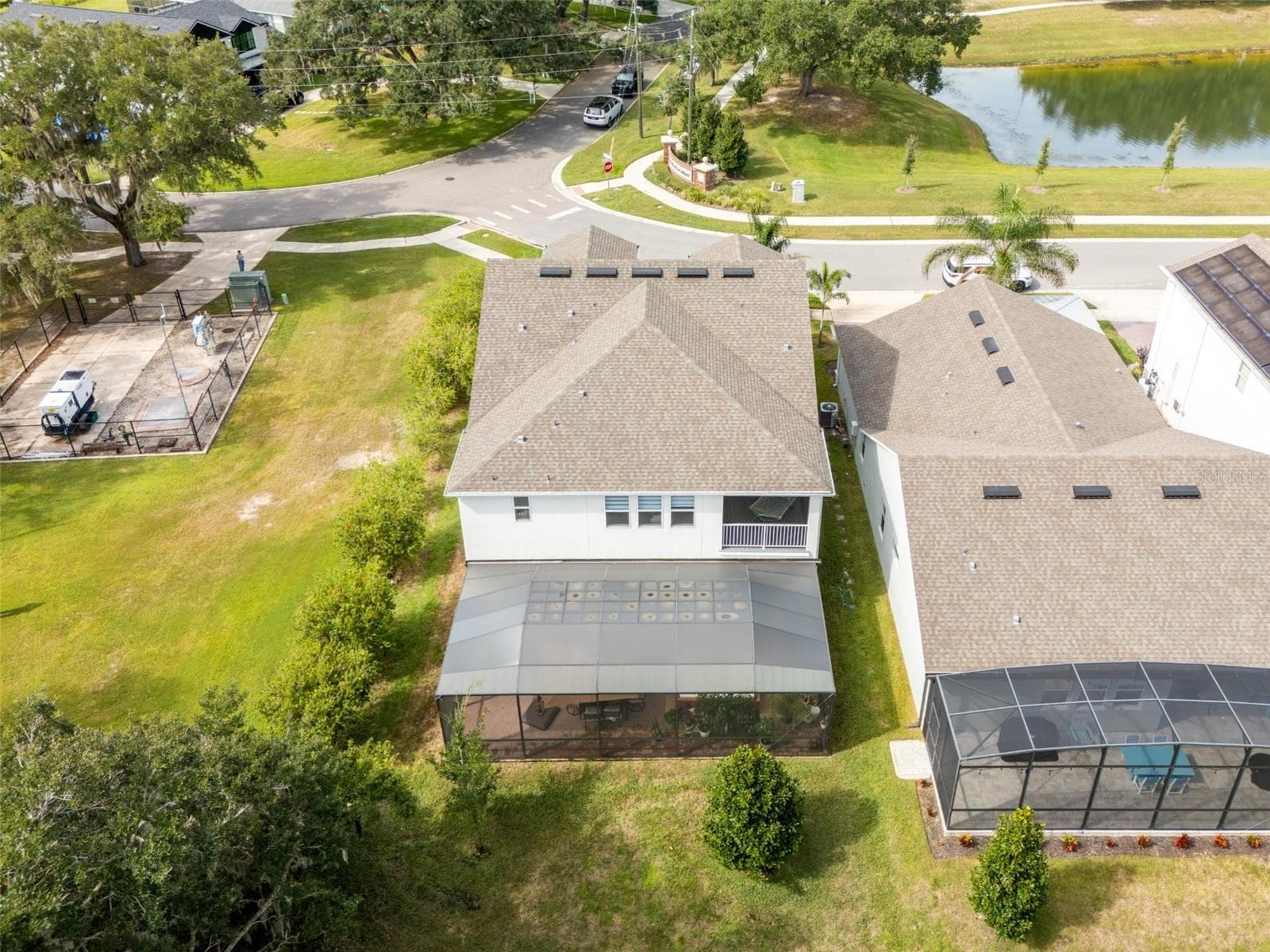 Rear aerial view showcasing an expansive screened patio, covered upstairs balcony, and wooded surroundings. - 1316 SOUTHERN SUN DRIVE, OAKLAND