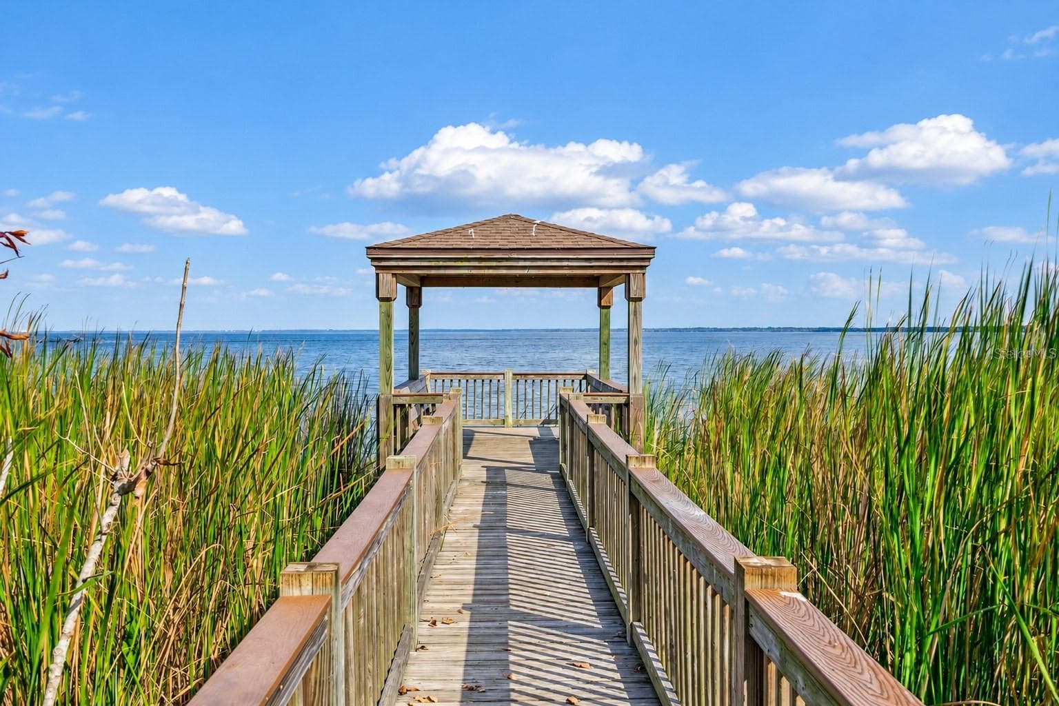 Community boardwalk leading to a covered lakeside gazebo with sweeping water views. - 1316 SOUTHERN SUN DRIVE, OAKLAND