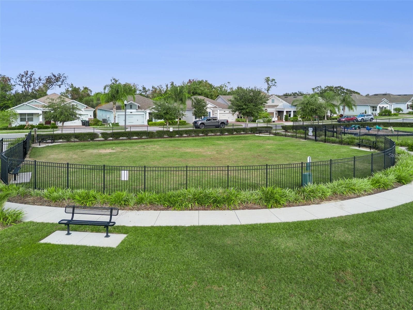 Fenced dog park with an open lawn, seating benches, and surrounding walking paths. - 1316 SOUTHERN SUN DRIVE, OAKLAND