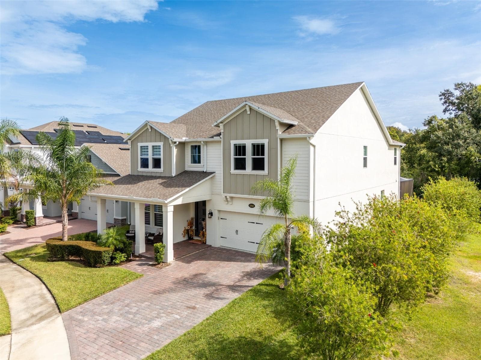 Elegant two-story home with a welcoming covered porch, paver driveway, and lush tropical landscaping. - 1316 SOUTHERN SUN DRIVE, OAKLAND