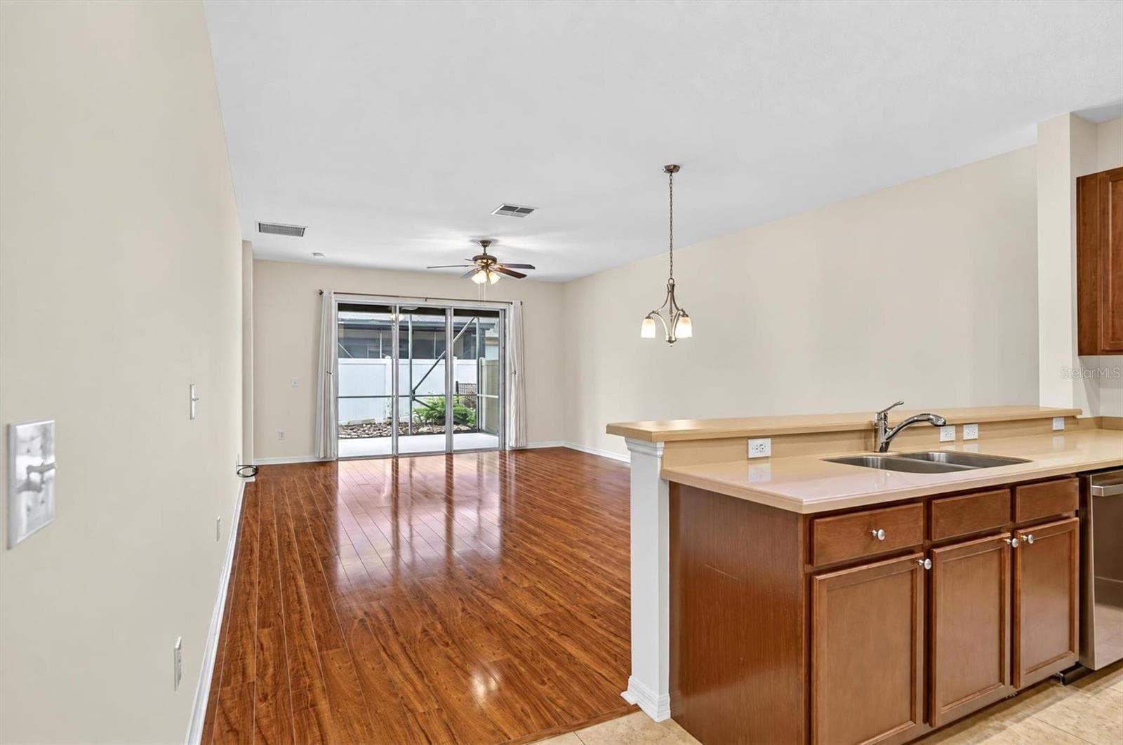 Kitchen / livingOpen-concept kitchen and living area with freshly painted neutral walls and hardwood flooring. - 2153 BARRACUDA CT, HOLIDAY