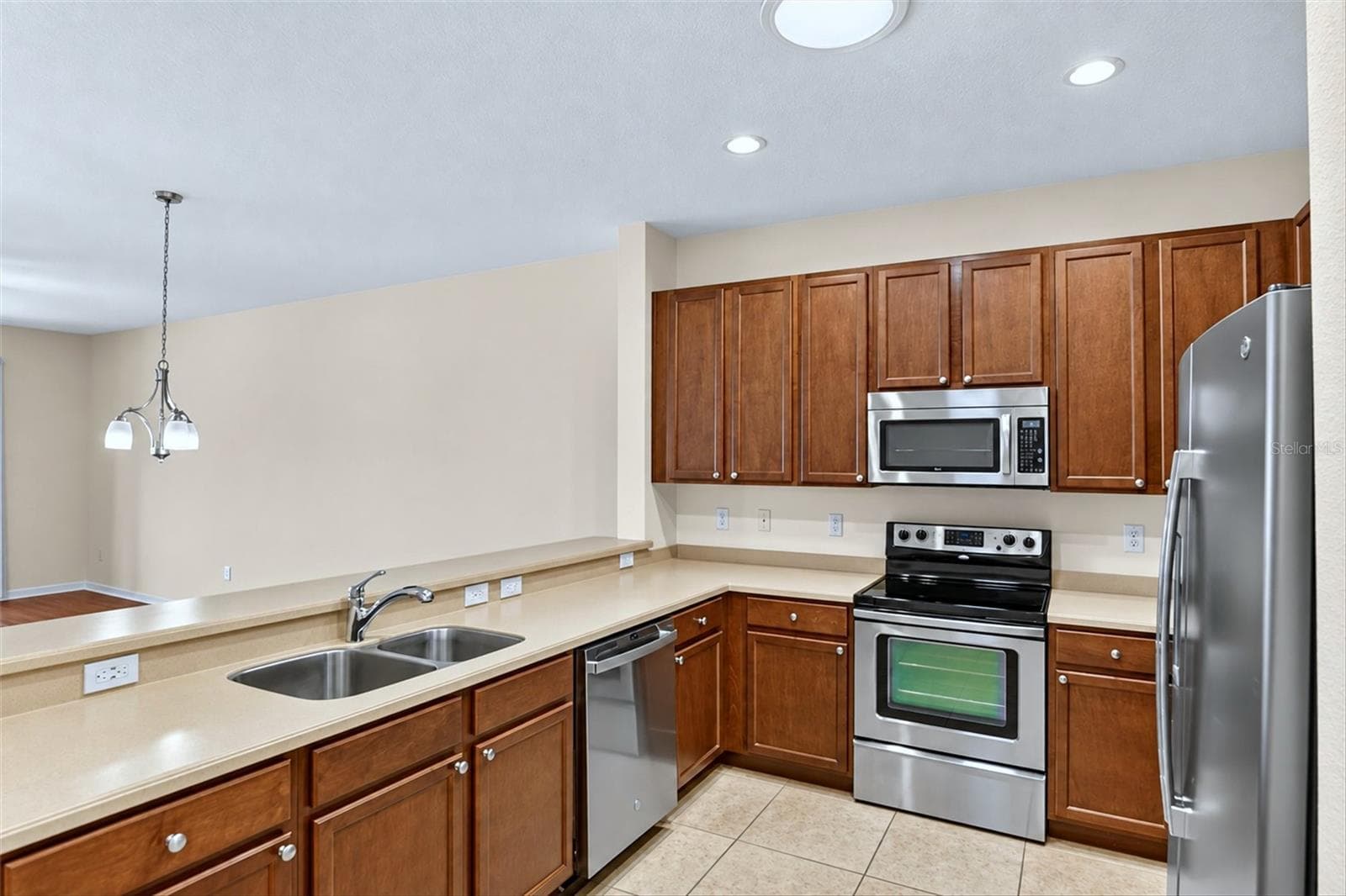 Kitchen with wood cabinetry, stainless steel appliances, breakfast bar and ample counter space. - 2153 BARRACUDA CT, HOLIDAY
